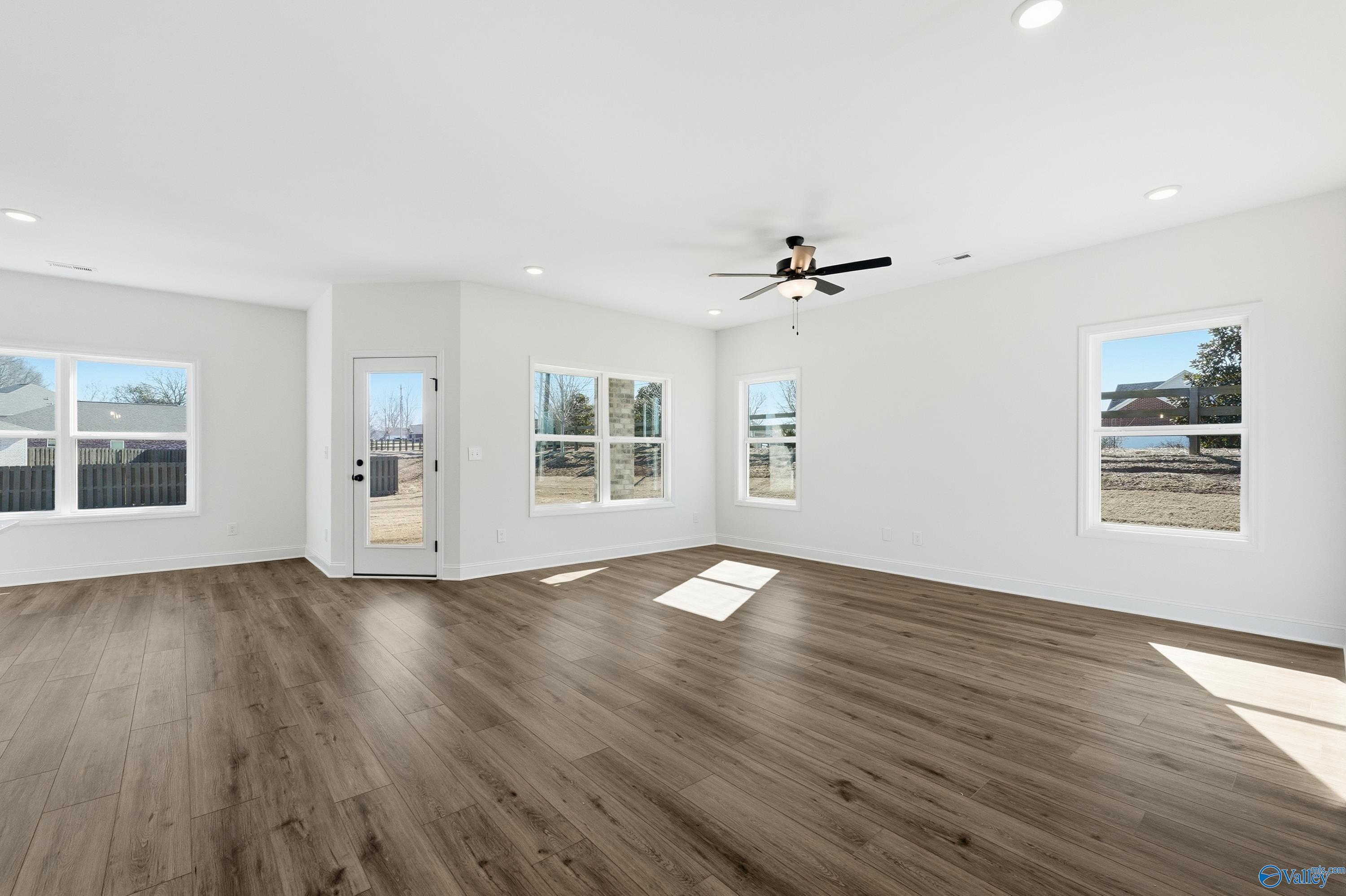 Bright living room with large sunny windows, ceiling fan, and hardwood floors in Davidson Homes The Franklin C, New Market, Alabama