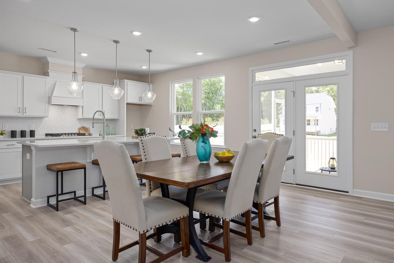 Open-concept kitchen and dining area in The Chestnut by Davidson Homes featuring a large island, modern lighting, and decor.