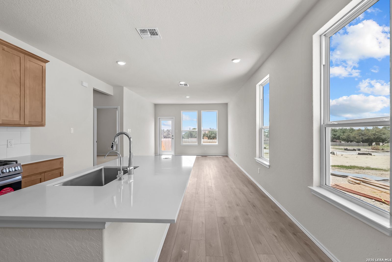 Bright open-concept kitchen island and living area in The Gillian B floor plan at Meadows at Oak Creek, San Antonio, Texas.