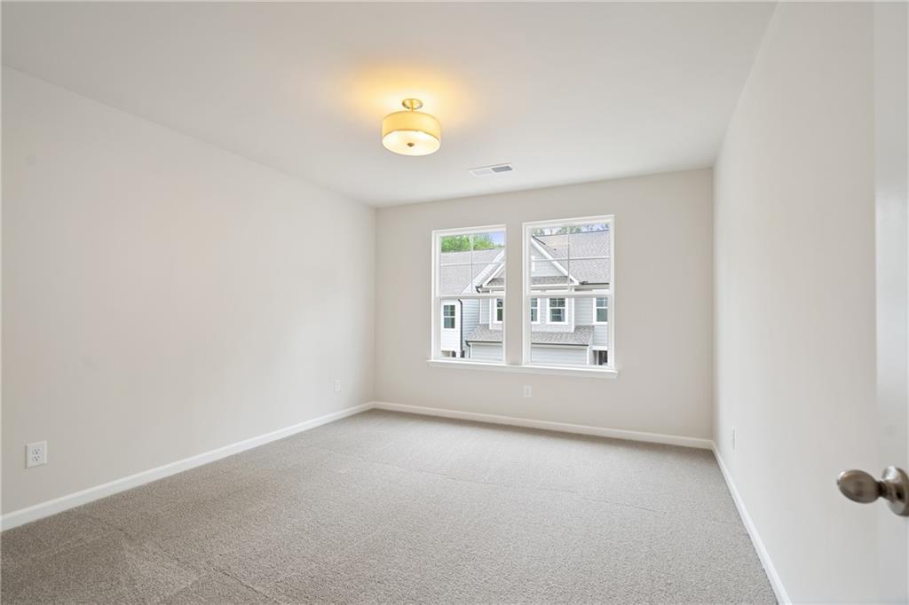 Bright secondary bedroom with beige walls, carpet floor, and large windows in Davidson Homes The Cary B, Kennesaw, Georgia