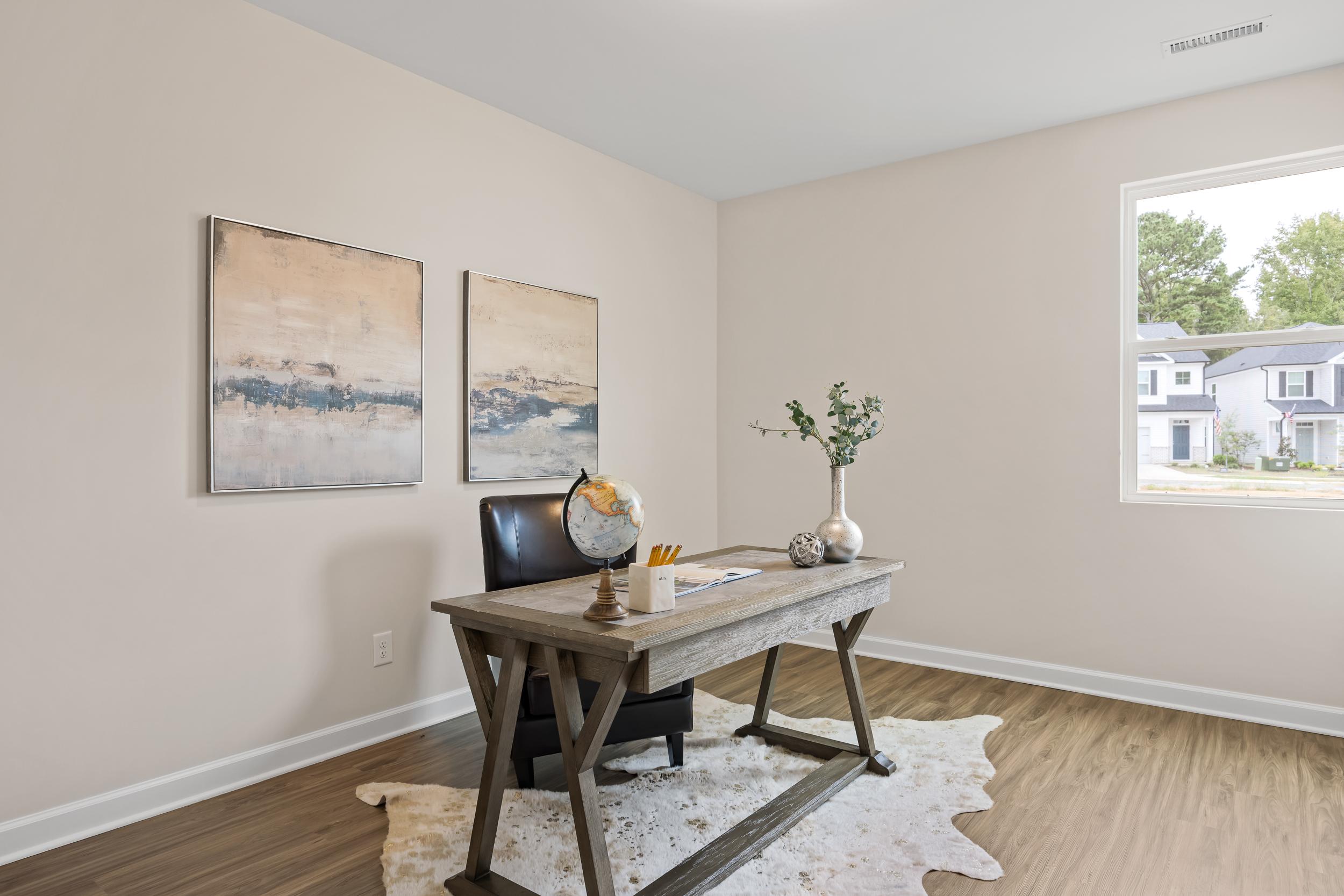 Cozy home office at Gregory Village in Lillington NC featuring wooden desk, leather chair, cowhide rug, and abstract art