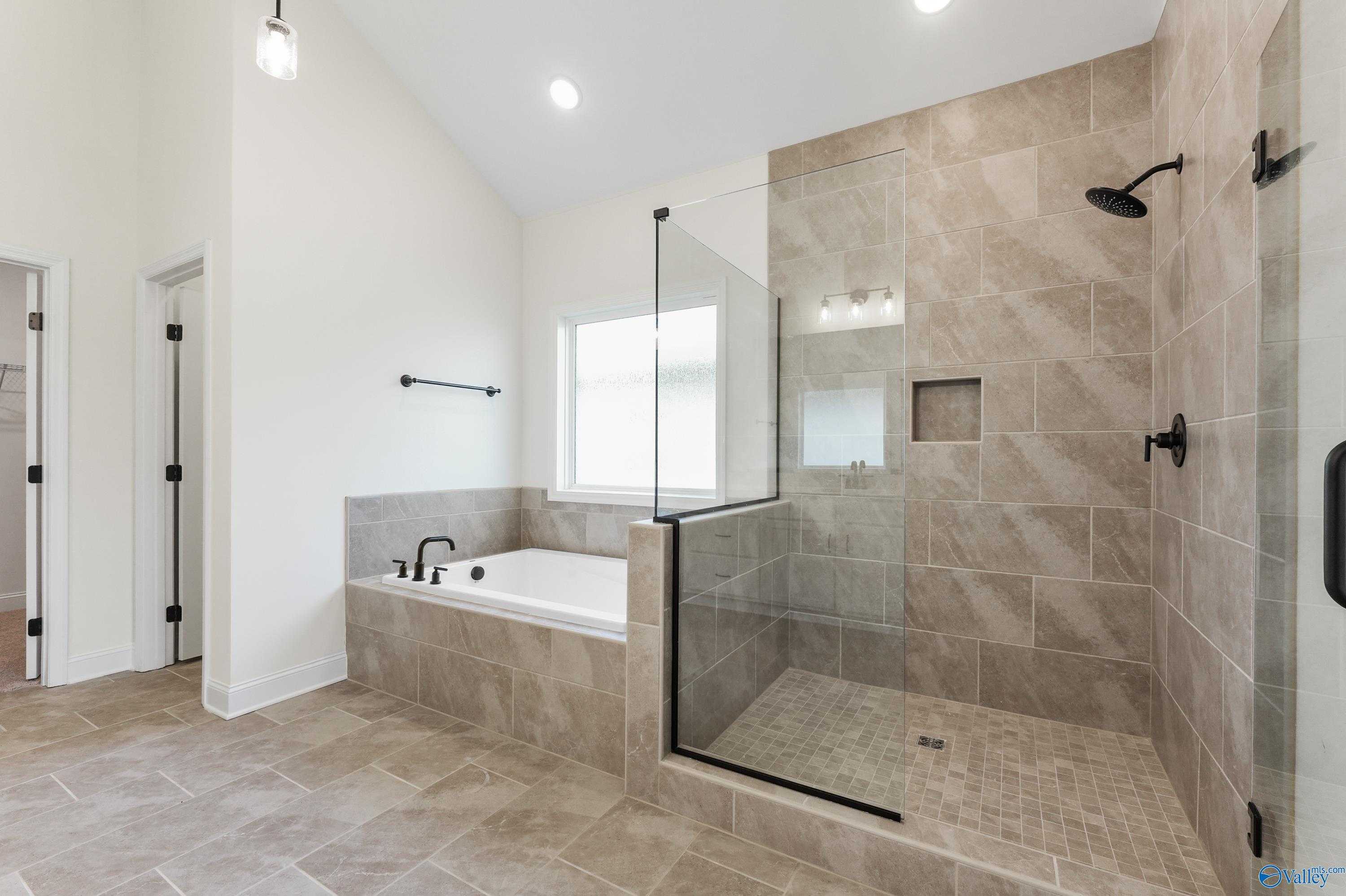 Elegant master bathroom with freestanding tub, tiled glass shower, and natural light in Davidson Homes The Finleigh, Harvest AL