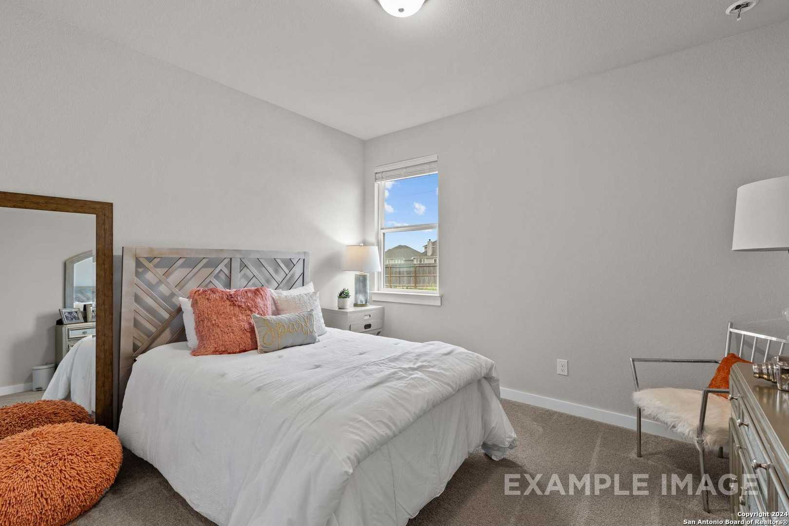Cozy bedroom with white bedding, orange accents, shiplap headboard, and window in Davidson Homes The Collin B, Seguin, Texas