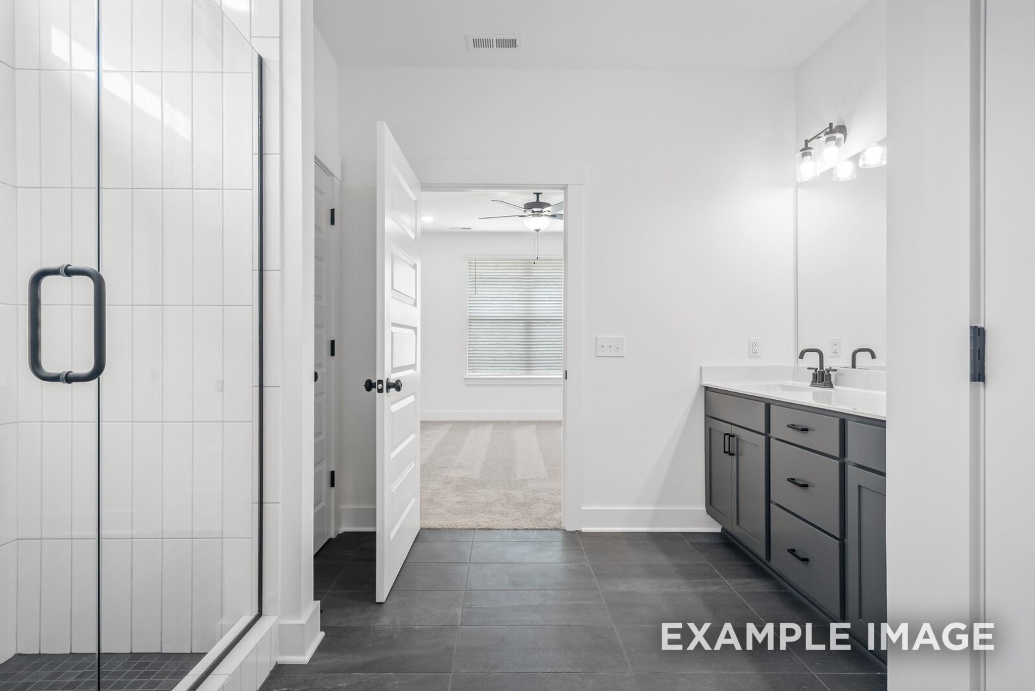 Modern master bathroom with frameless glass shower, double vanity, and dark cabinets in Davidson Homes The Ridgeport C, Gallatin, TN