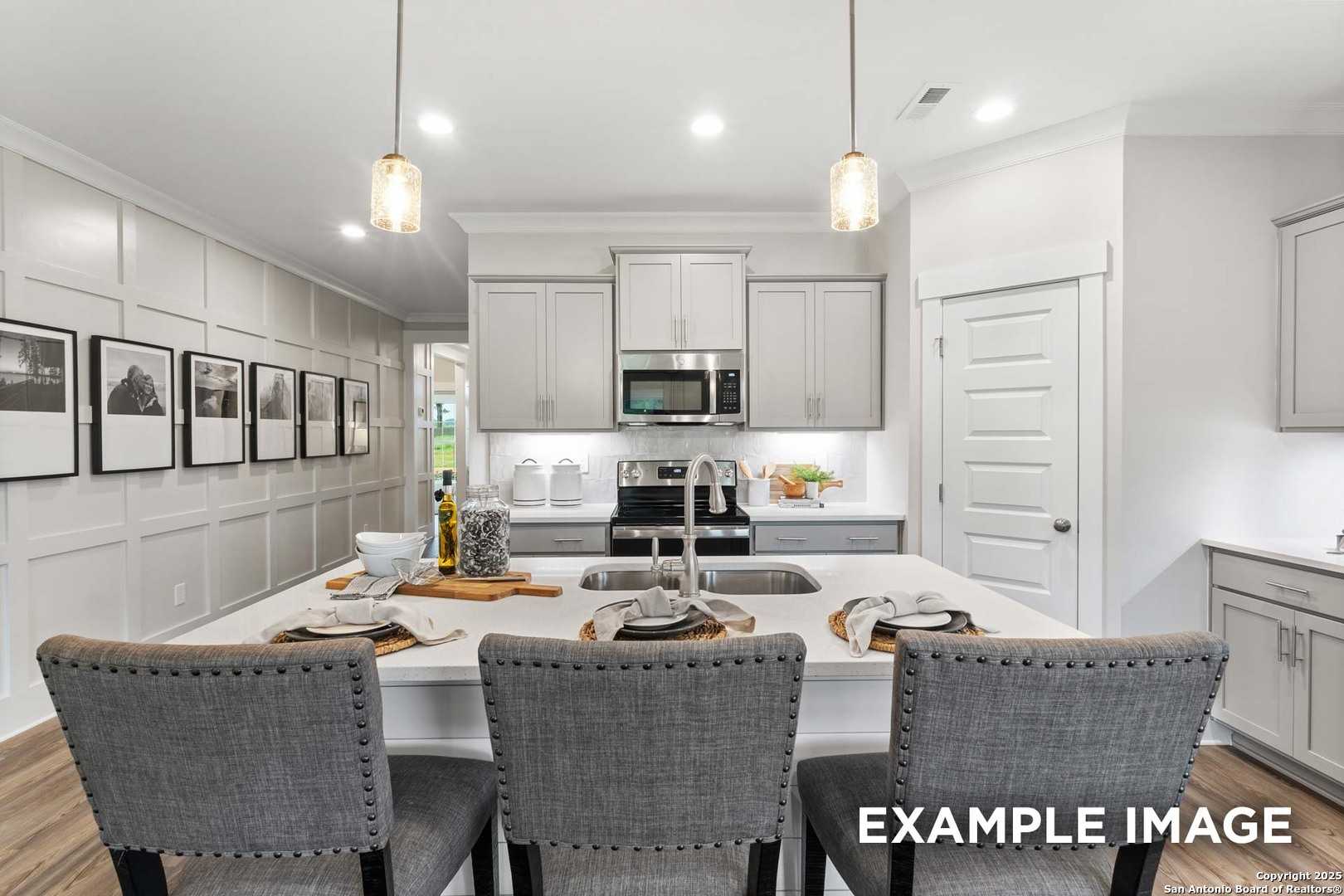 Modern open-concept kitchen with white shaker cabinets, stainless appliances, and island seating in Davidson Homes The Daphne H, Seguin, Texas