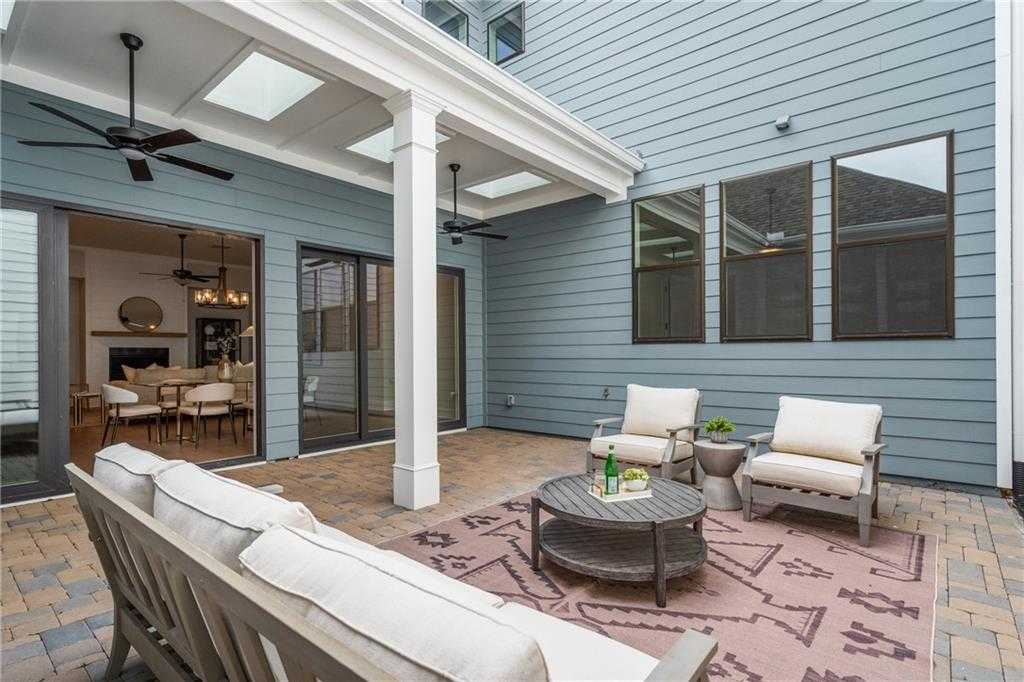 Covered patio with cushioned seating, coffee table, ceiling fans, and living room view in Davidson Homes Seaside B, Woodstock, GA