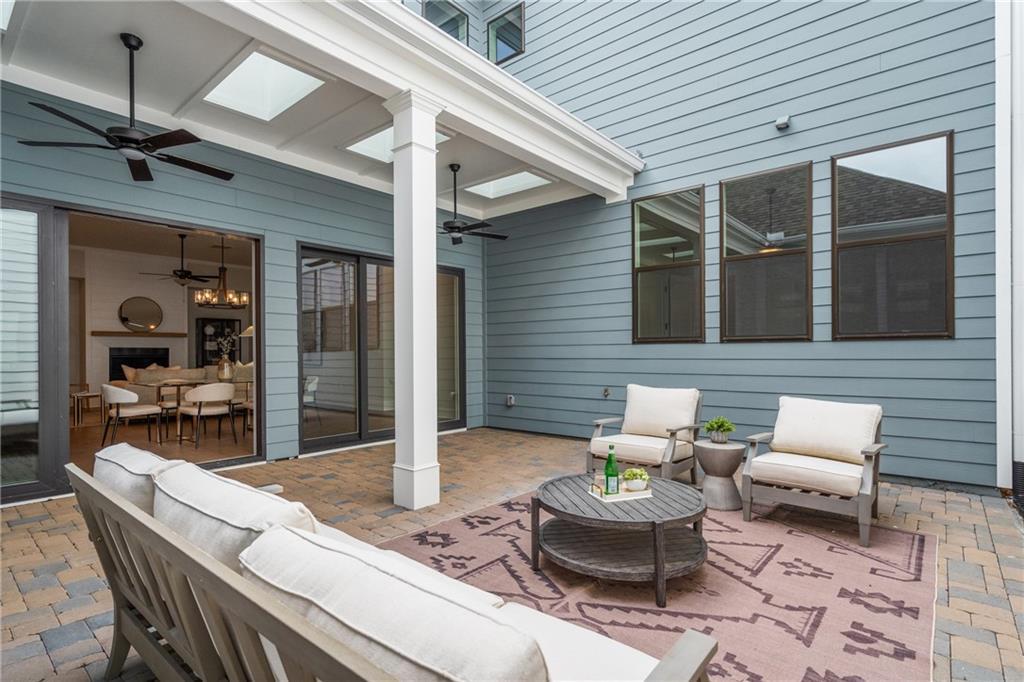 Covered patio with cushioned seating, coffee table, ceiling fans, and living room view in Davidson Homes Seaside B, Woodstock, GA