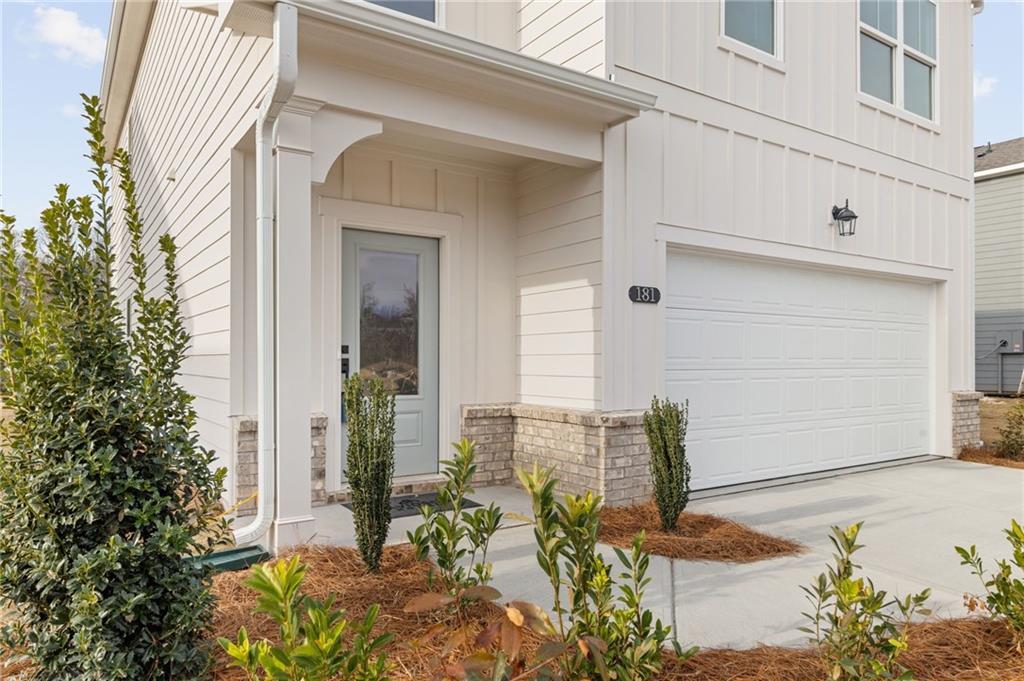 Charming two-story white home with covered front porch, glass door, two-car garage, and landscaped yard in Cedar Farms, Winder, Georgia - Davidson Homes The Rabun C