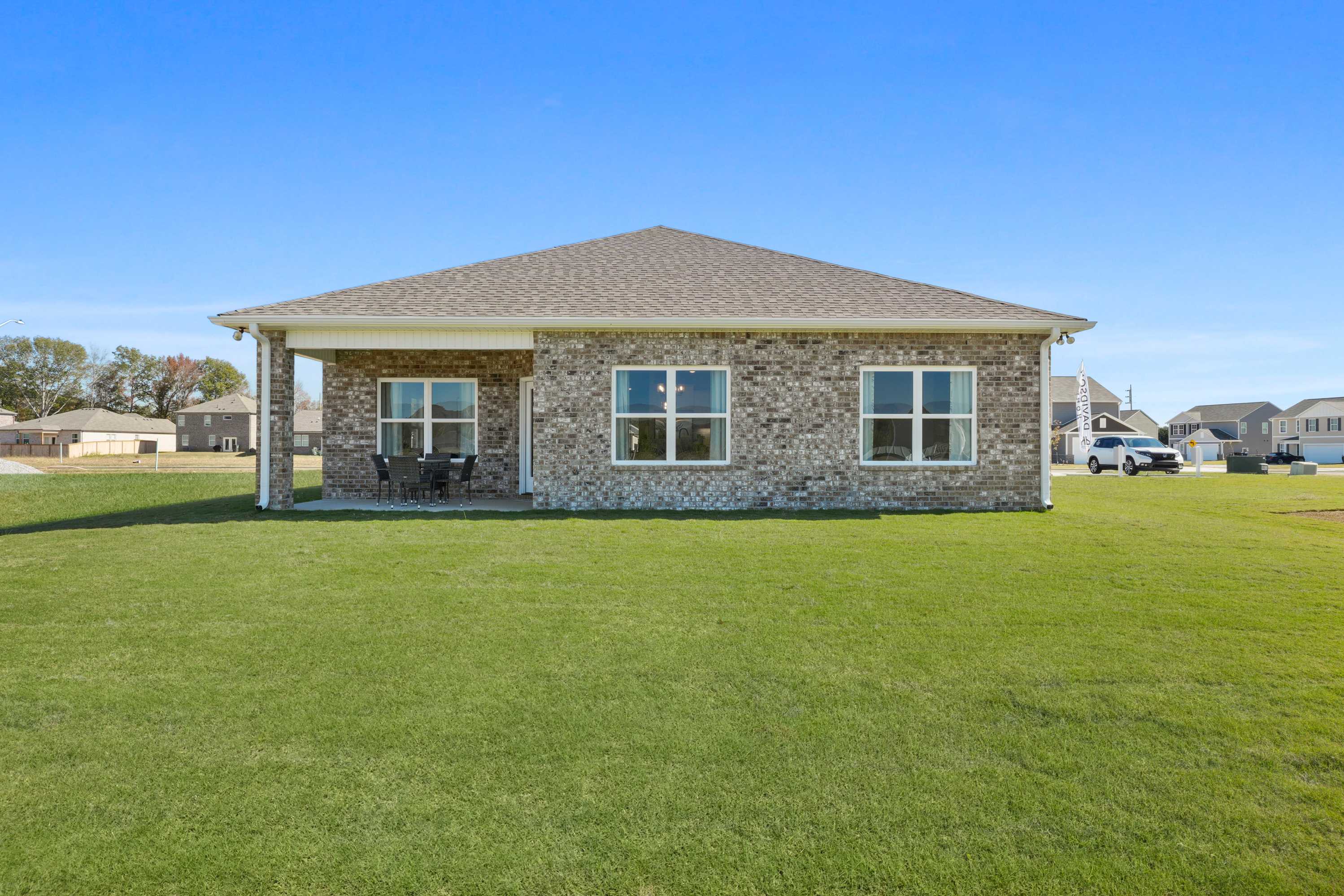 Brick ranch home exterior at Ramsay Cove in Owens Cross Roads, Alabama with covered porch, large windows, and lush green lawn