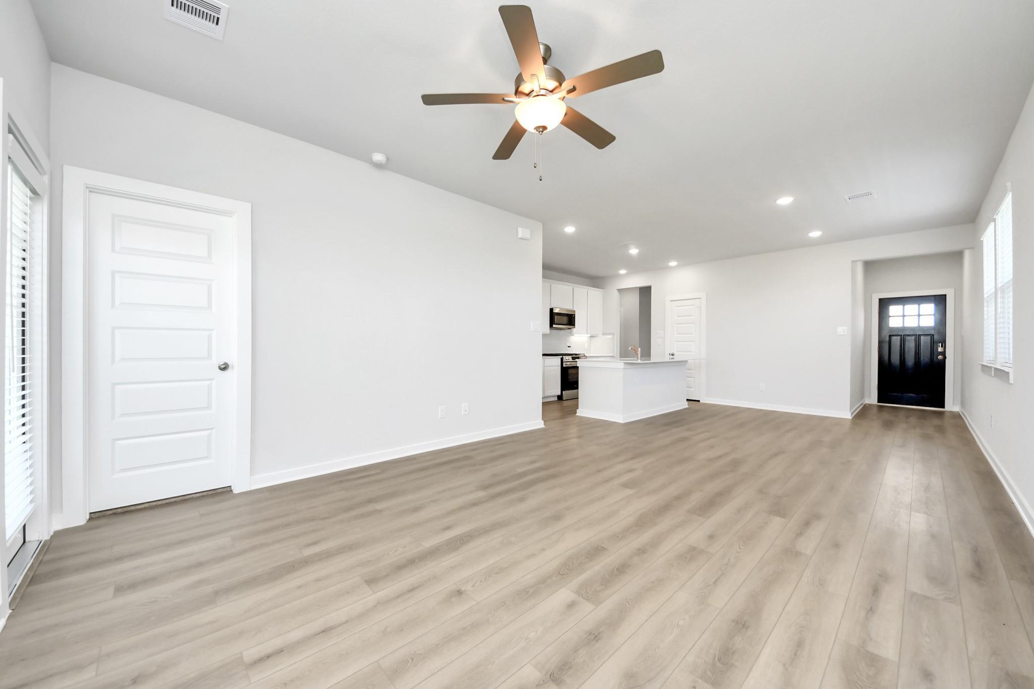 Open-concept living area with luxury vinyl plank flooring and ceiling fan in The Costa A by Davidson Homes, Beasley, TX