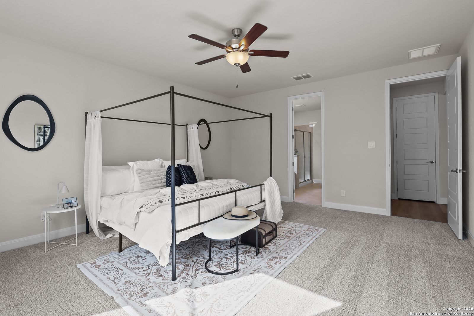 Elegant master bedroom with white canopy bed, ceiling fan, and en-suite bath in Davidson Homes The Lanier H, Ladera, San Antonio