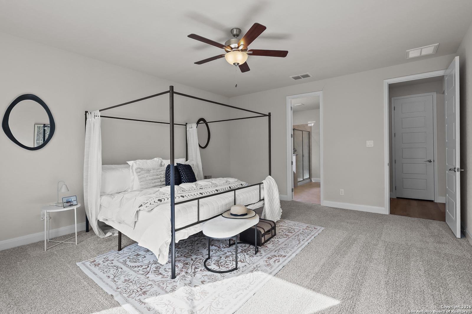 Elegant master bedroom with white canopy bed, ceiling fan, and en-suite bath in Davidson Homes The Lanier H, Ladera, San Antonio