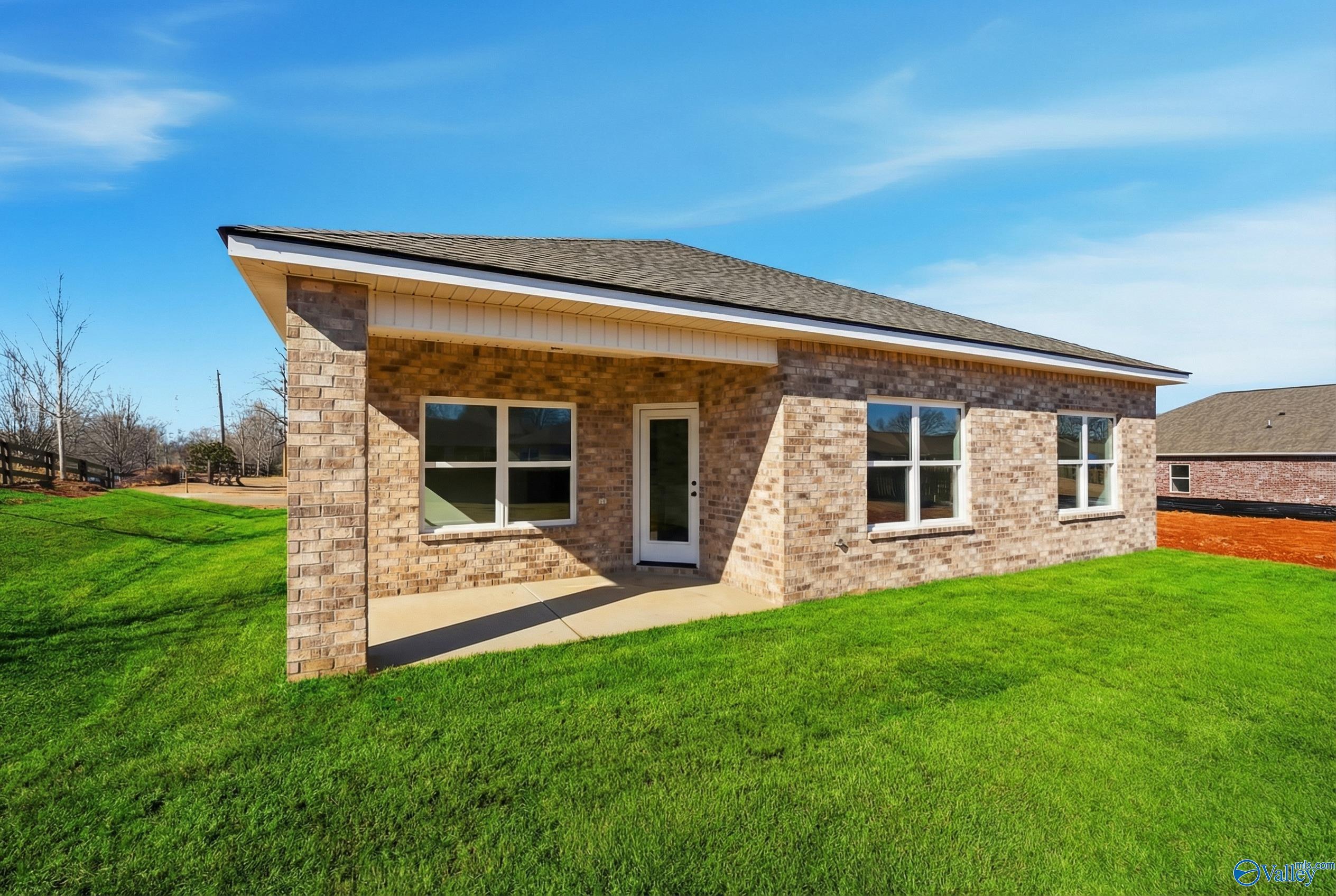 Brick one-story home exterior with gabled roof, front entry, and green lawn in Flint Meadows, New Market, Alabama