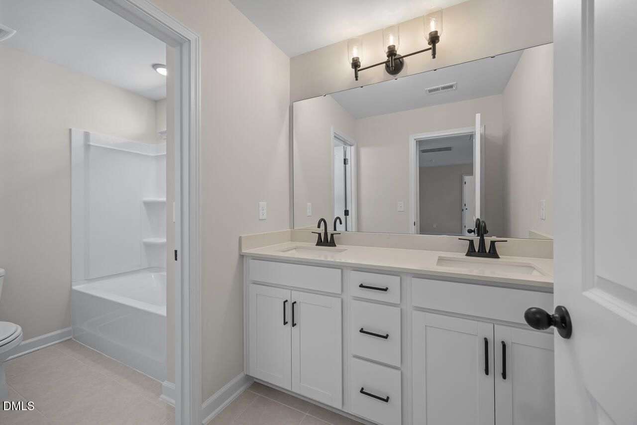 Double vanity bathroom with white cabinets, black hardware, and tub in Davidson Homes Ashport M plan, Wendell Ridge, NC