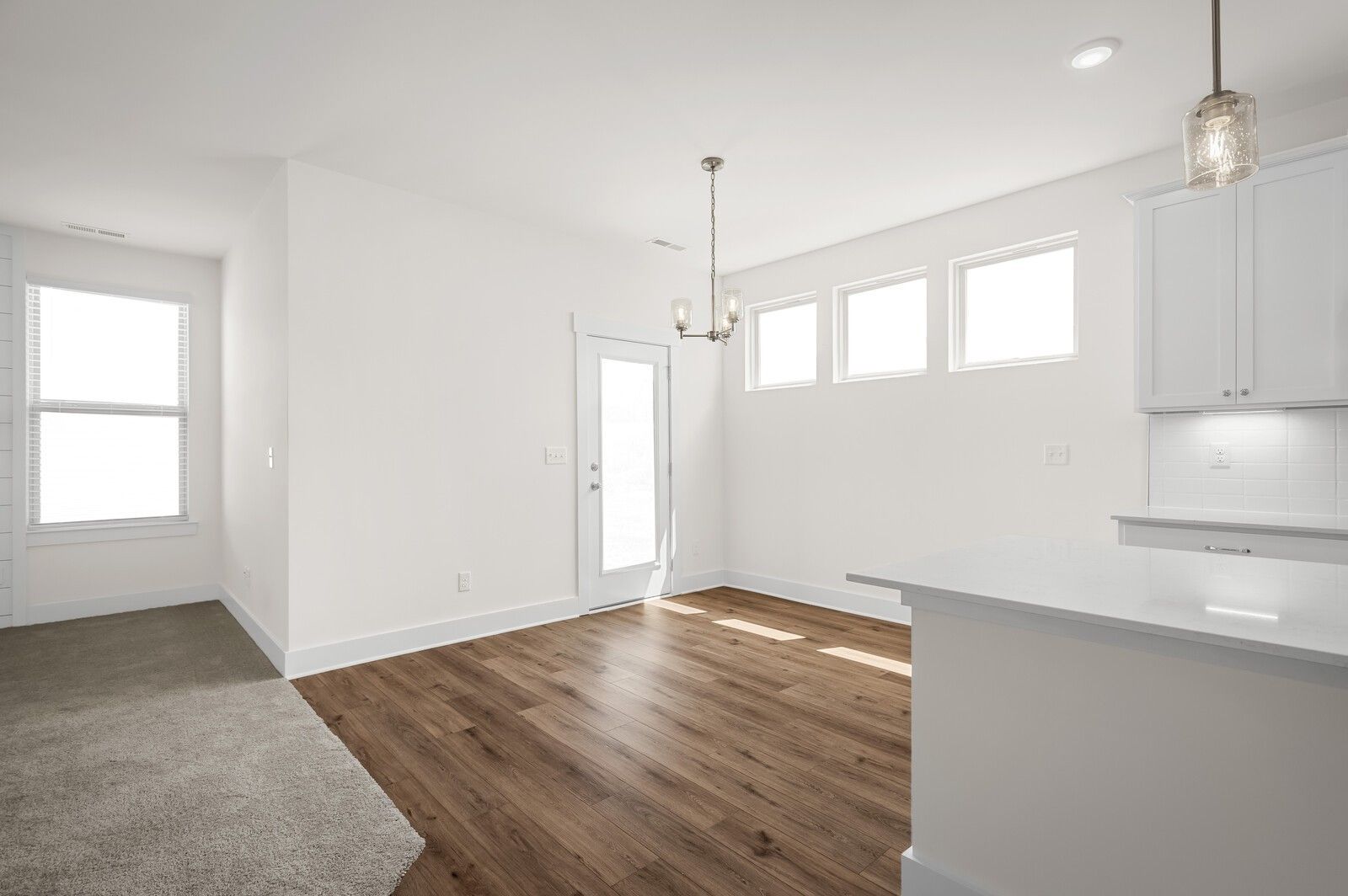 Bright dining area with hardwood floors, chandelier, and natural light in The Ash A floor plan at Woods Crossing, Gallatin.