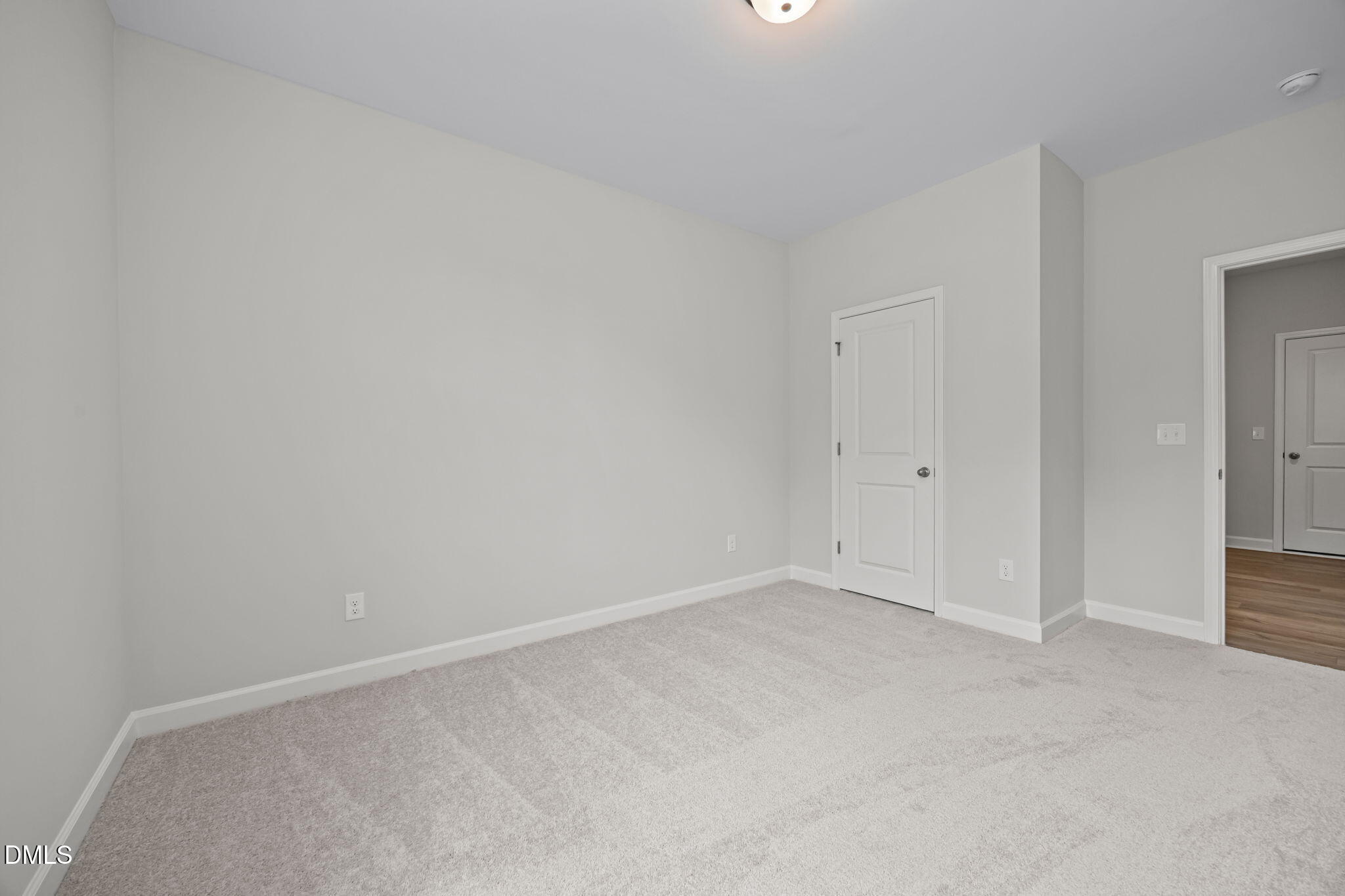 Empty secondary bedroom featuring gray walls, plush carpet, and double doors in Davidson Homes The Willow D, Wendell, NC