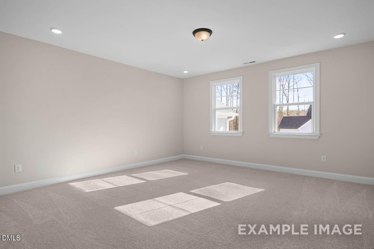 Bright bedroom with neutral beige walls, carpet floor, large sunny windows in 4-bed The Crawford D home, Angier, NC