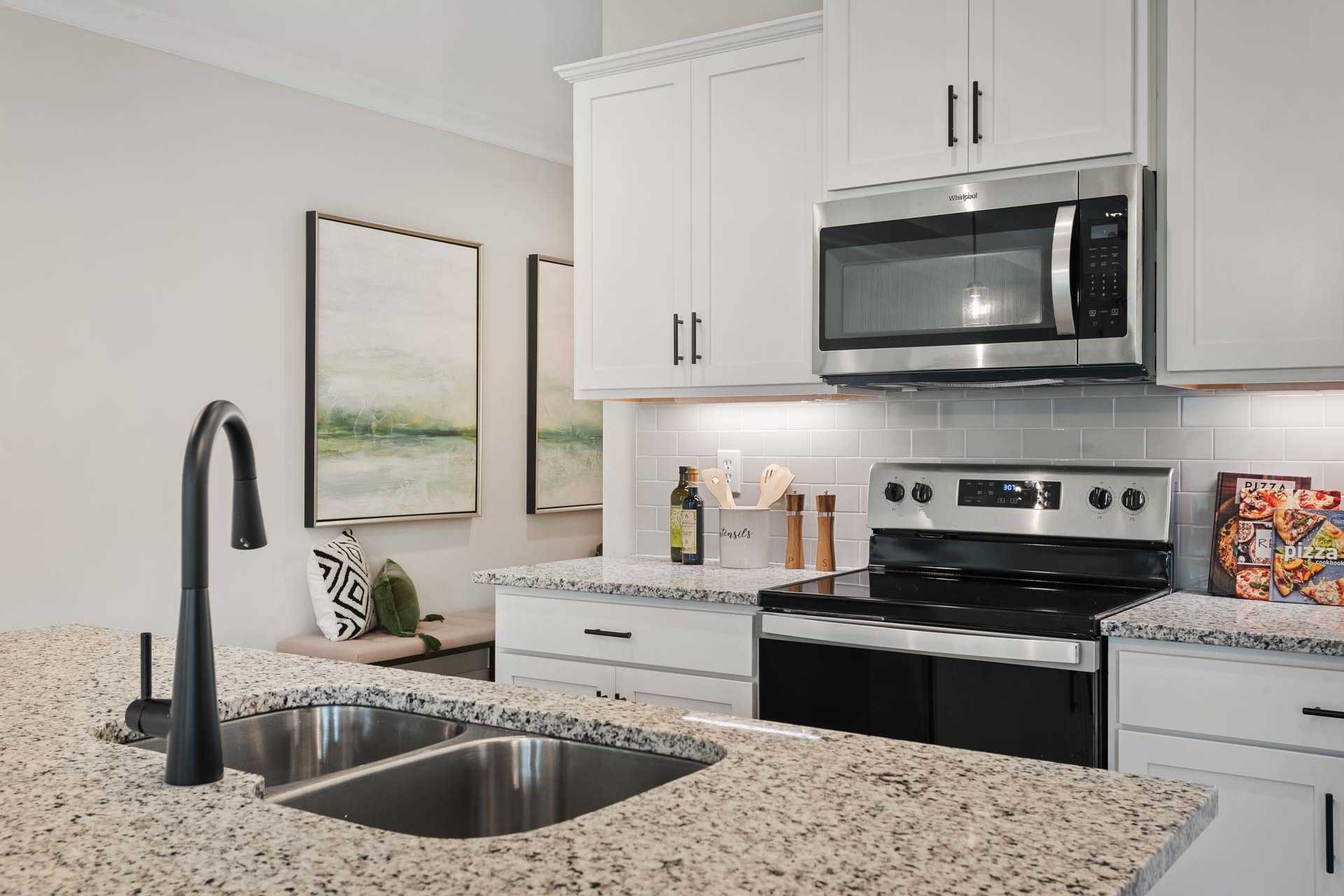 Spacious kitchen in Durham Farms Harvest Alabama with white shaker cabinets granite counters stainless steel appliances