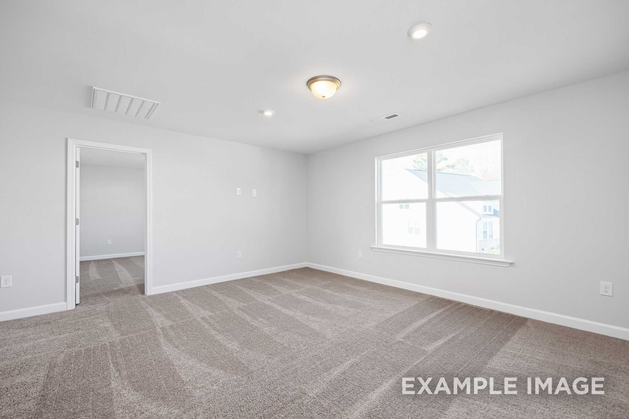 Spacious empty master bedroom in The Cypress D II with light gray walls, neutral carpet, and large window
