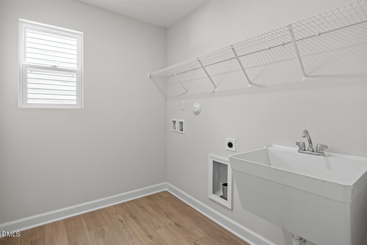 Laundry room with utility sink and wire shelving in The Gavin A floor plan at Gregory Village, Lillington, North Carolina.