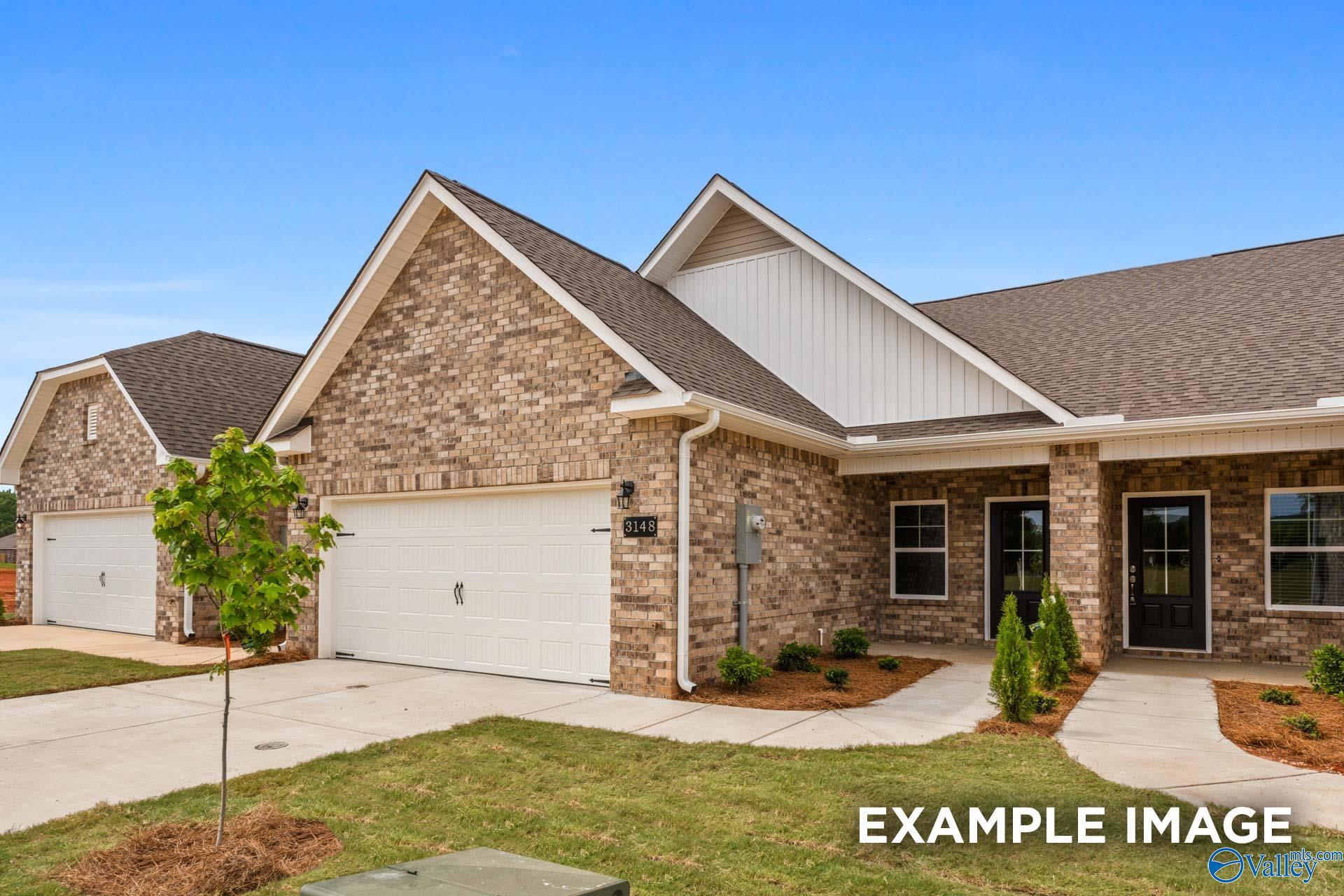 Single-story brick home with 2-car garage, white trim, front porch, and landscaped yard in The Retreat at Hollon Meadow, Decatur, Alabama