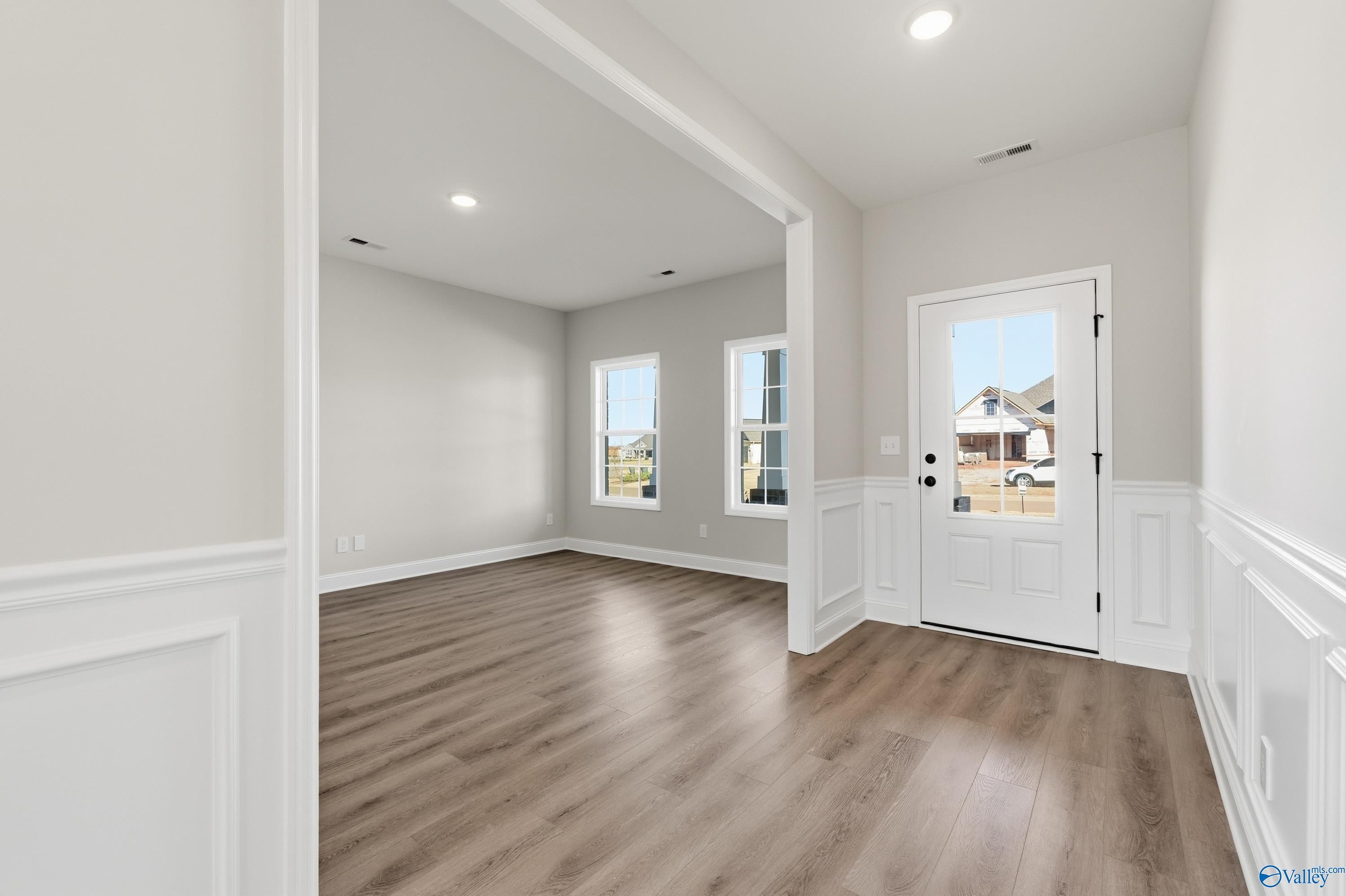 Bright entry foyer with hardwood floors, white wainscoting, and sidelight windows in Davidson Homes The Chelsea C, Creekside, Harvest, Alabama