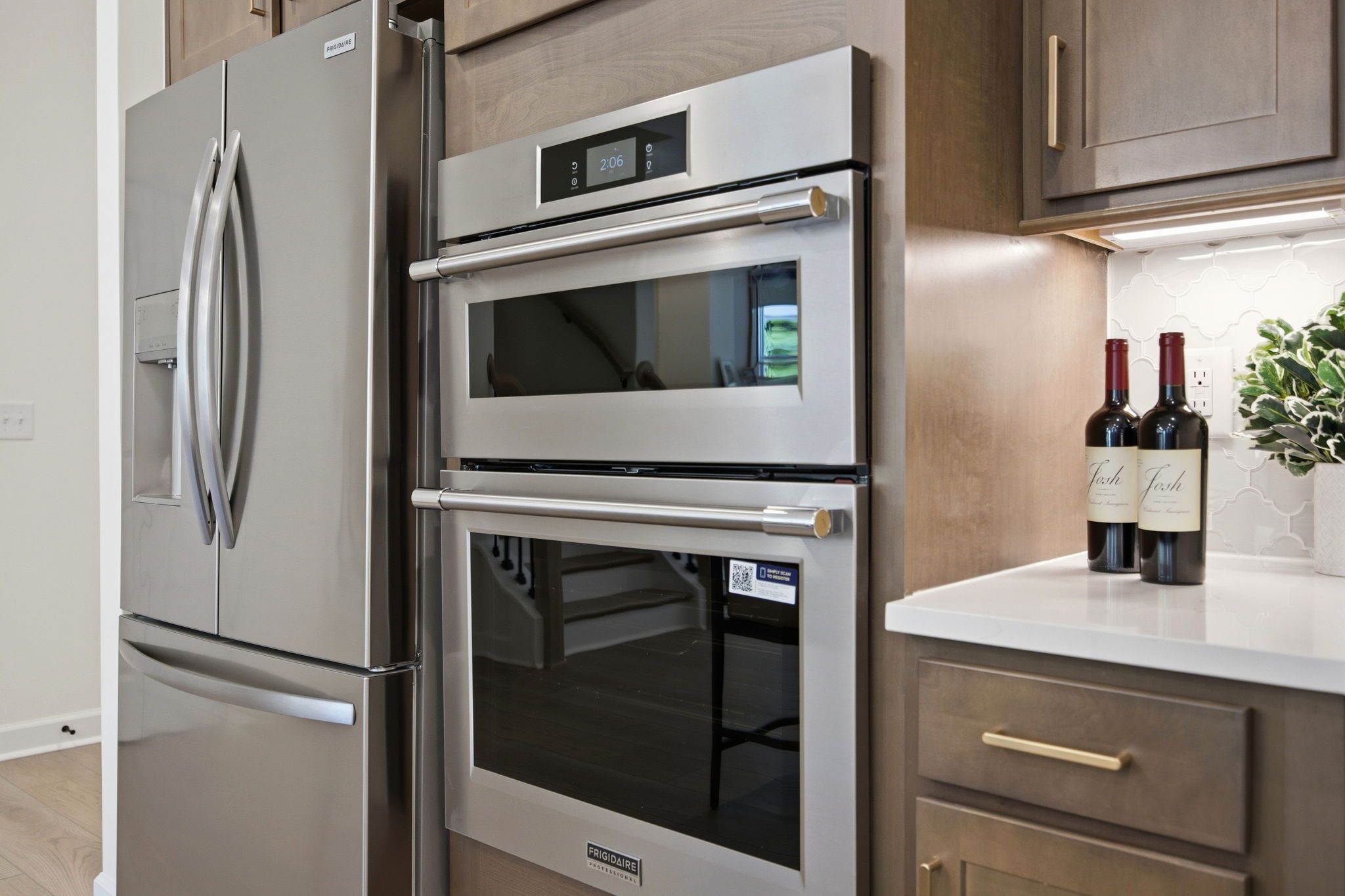 Modern kitchen in The Ashport featuring stainless steel Frigidaire double wall ovens, refrigerator, and quartz countertops.