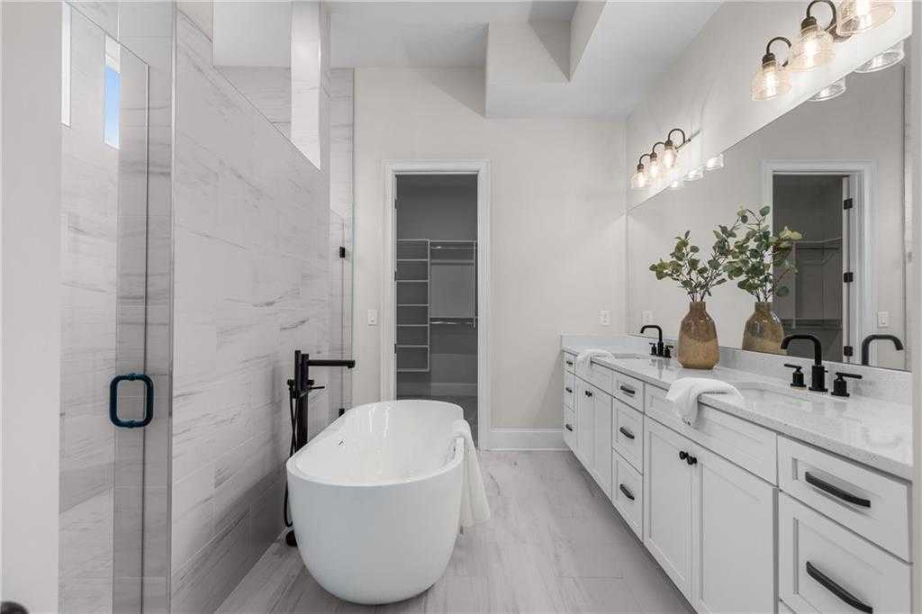 Elegant master bathroom with freestanding tub, double quartz vanity, and glass shower in Davidson Homes The Seaside B, Woodstock, GA