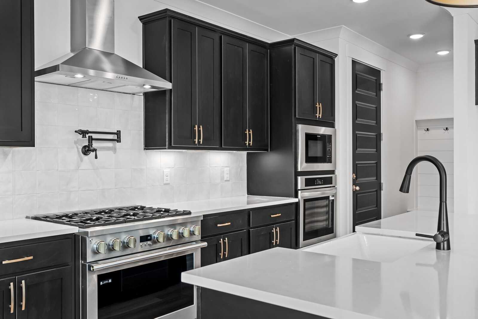 Modern kitchen featuring black shaker cabinets, white quartz island, gas range, and stainless appliances in Davidson Homes The Hathaway, Murfreesboro, TN
