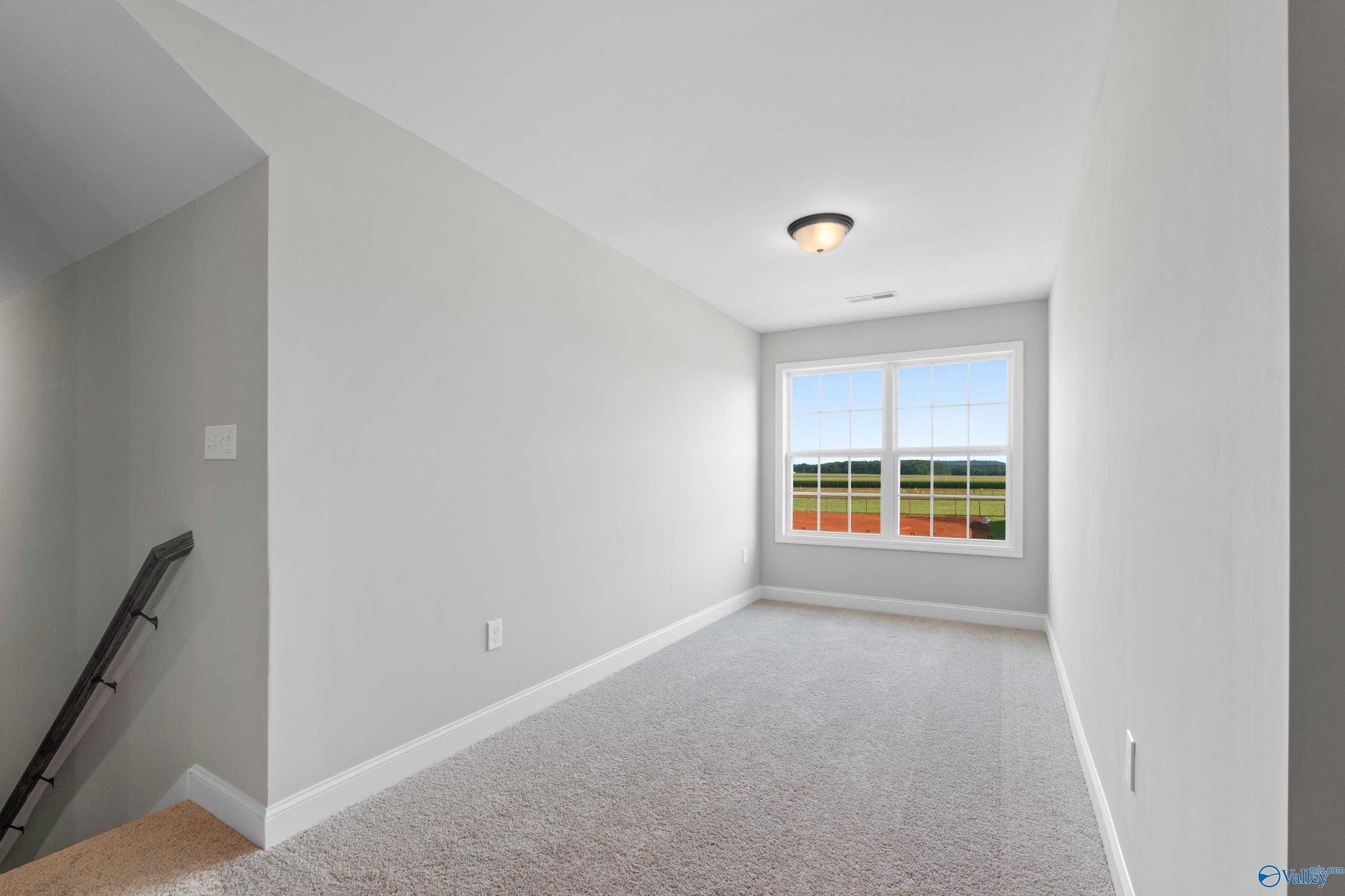 Bright bedroom with gray walls, carpet floor, large window view of fields in Davidson Homes The Rockford with Bonus, Toney, AL