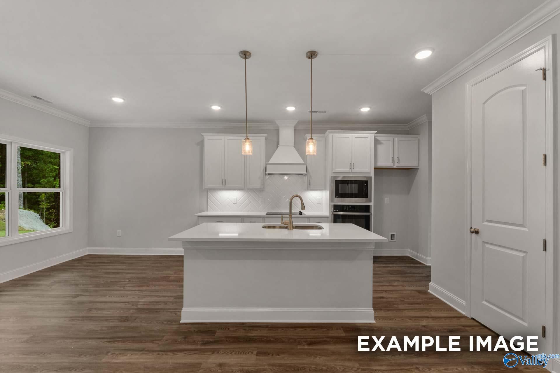 Modern white kitchen with quartz island, subway tile backsplash, and pendant lights in Davidson Homes Shelby C, Arab, Alabama