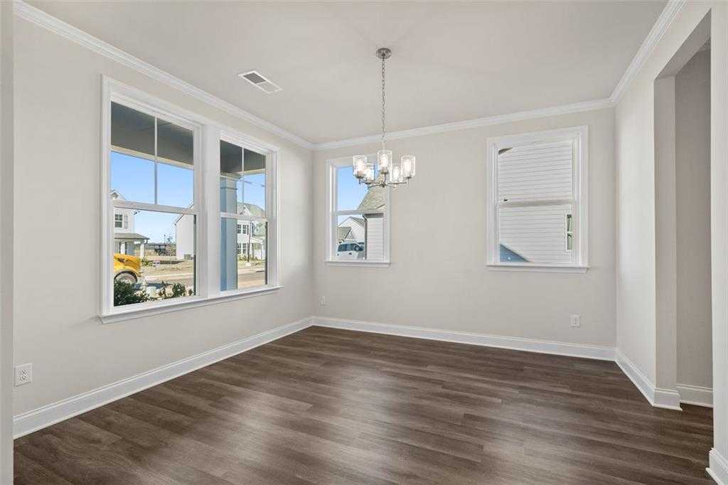 Bright dining room with large windows, chandelier, and hardwood floors in Davidson Homes The Ash C at Wehunt Meadows, Hoschton, Georgia