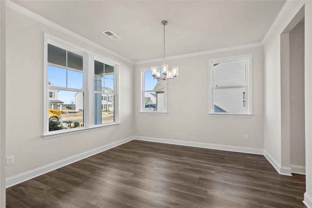 Bright dining room with large windows, chandelier, and hardwood floors in Davidson Homes The Ash C at Wehunt Meadows, Hoschton, Georgia