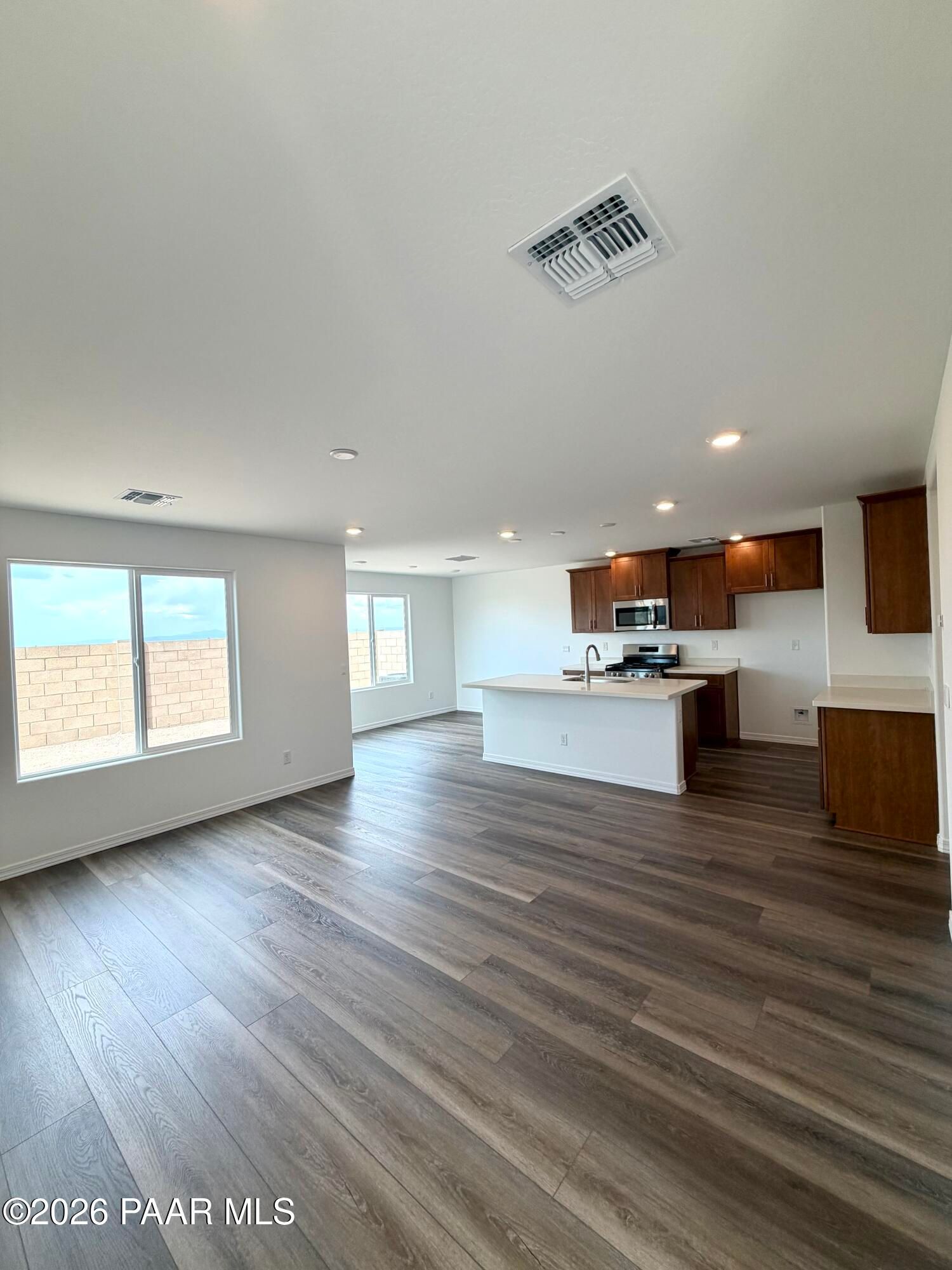 Open-concept kitchen and living area with wood-style flooring in The Raleigh A floor plan at South Ranch, Prescott, AZ.