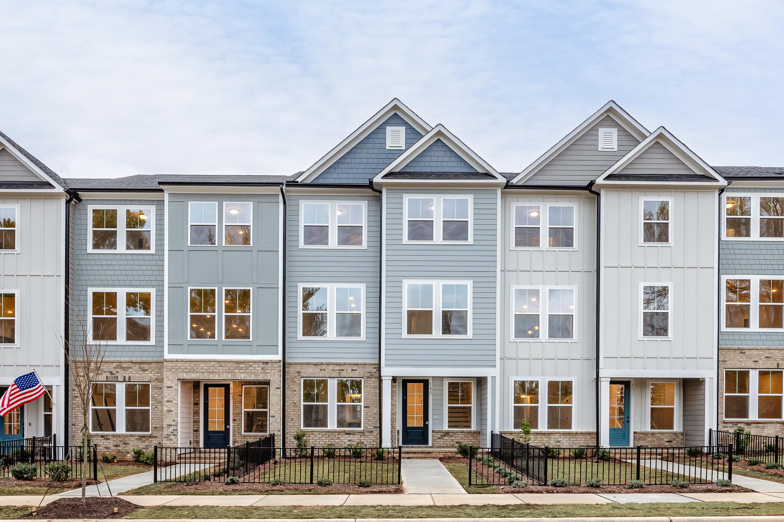 Row of modern townhomes with gray siding and brick bases at Forestville Yard in Knightdale NC