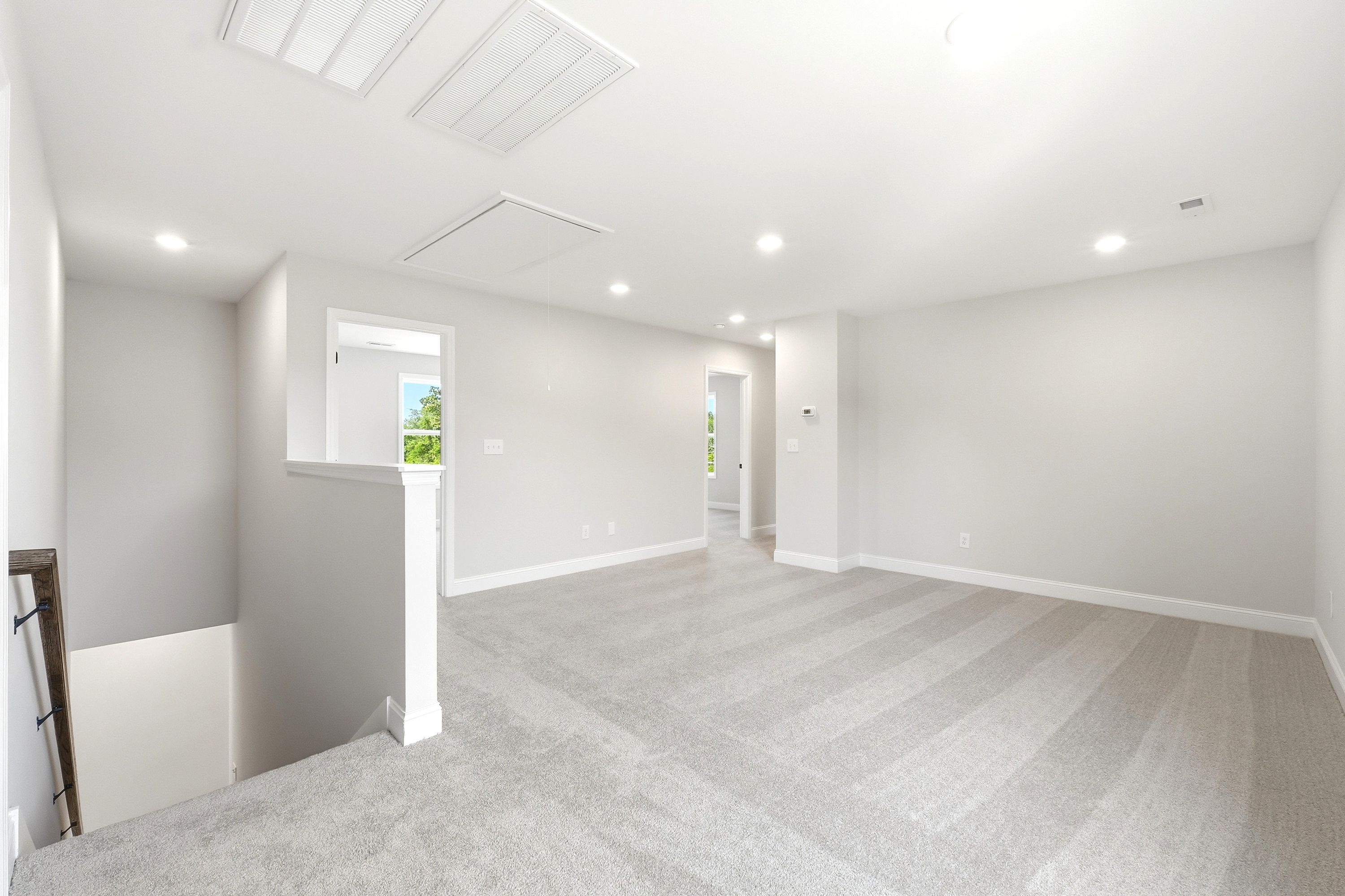 Spacious upper-level loft area in The Russell A floor plan featuring neutral carpeting and access to bedroom suites.