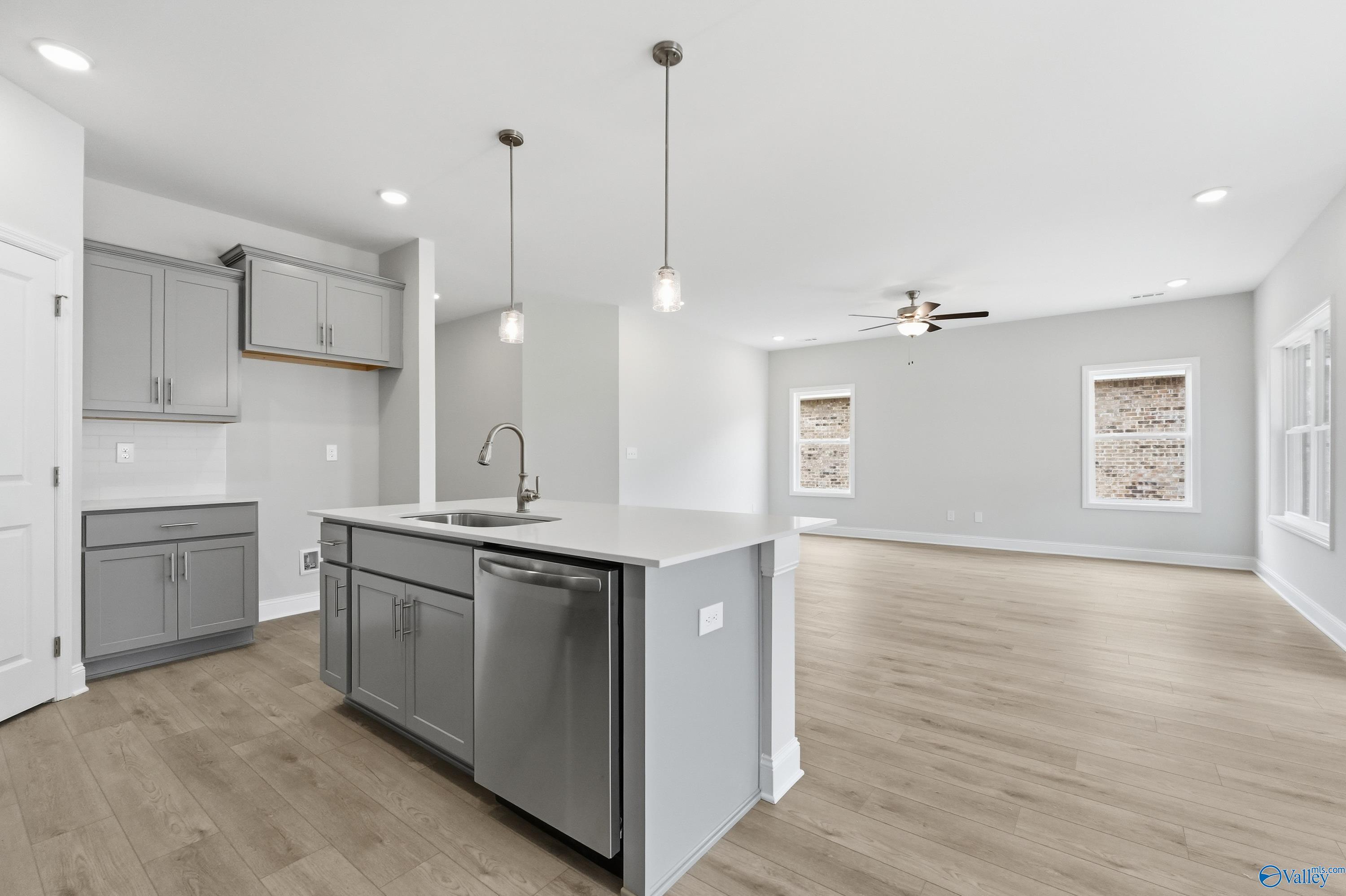 Open-concept kitchen with gray shaker cabinets, white quartz island sink, pendant lights, and adjacent living space in The Franklin by Davidson Homes, Meridianville, AL