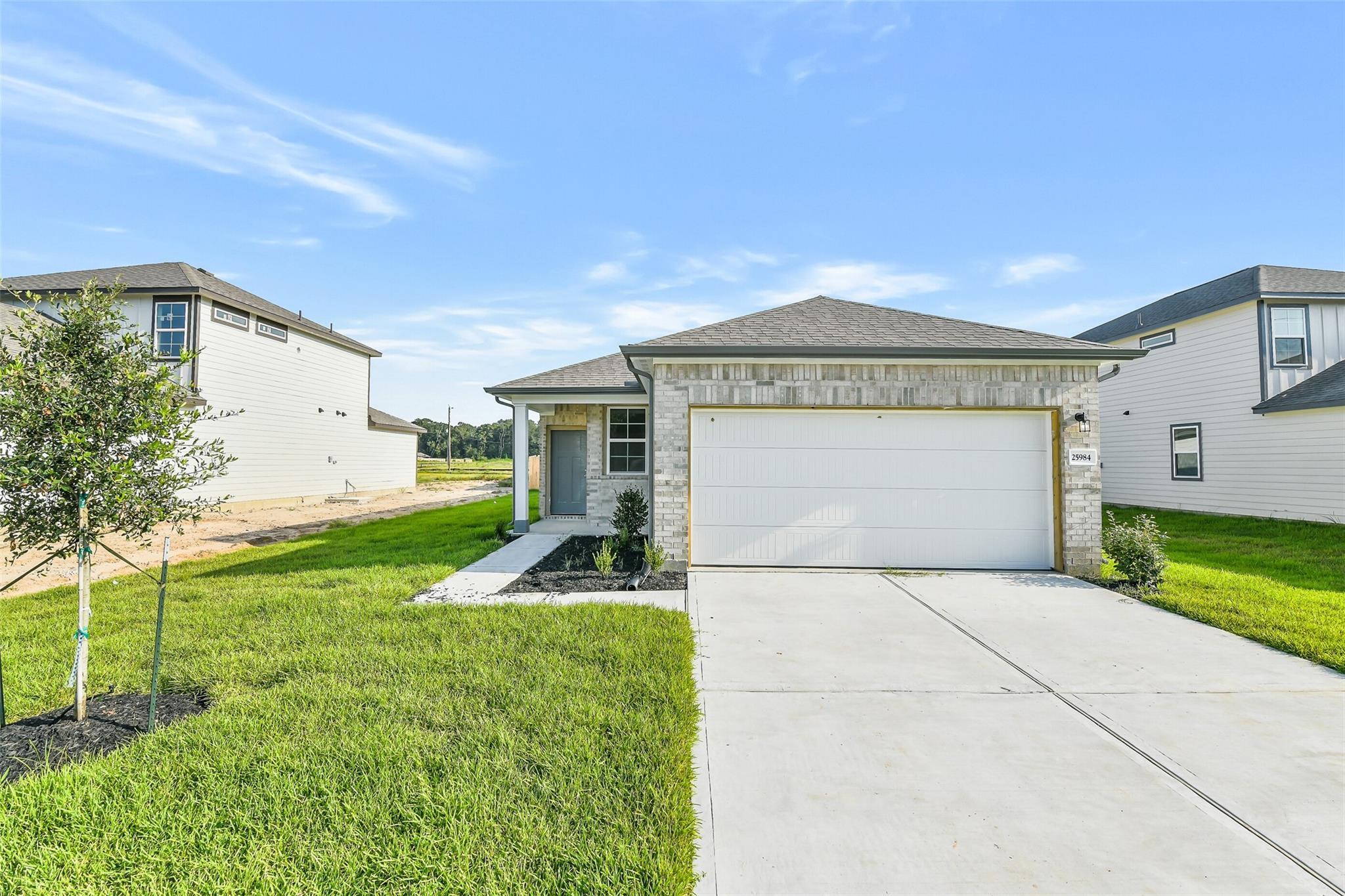 Modern single-story 4-bedroom home with 2-car garage, covered porch, and green lawn in Liberty Estates, Cleveland, Texas