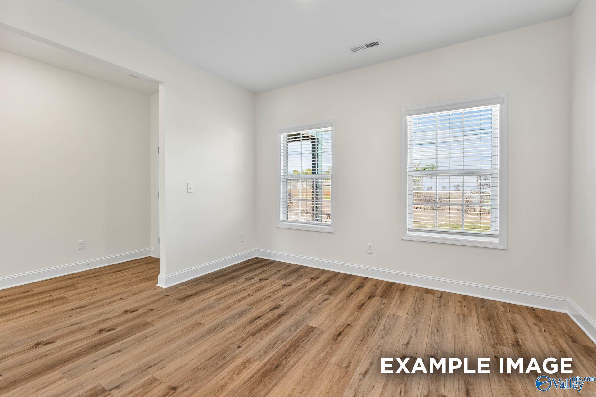 Bright secondary bedroom with hardwood floors, white walls, and large windows in Davidson Homes The Shelby A, Toney, Alabama