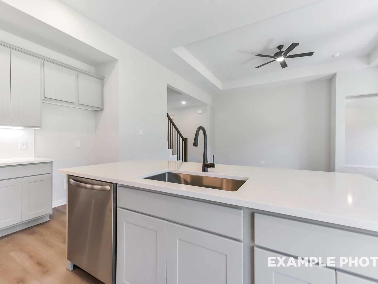 Modern kitchen island with quartz countertops and stainless steel sink in The Sequoia C floor plan, Sundance Cove, Crosby.