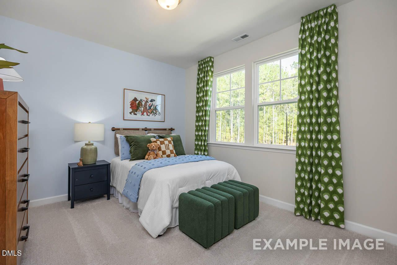 Cozy child's bedroom with blue walls, twin bed, fox artwork, and green polka-dot curtains in The Hickory II C, Wake Forest, NC