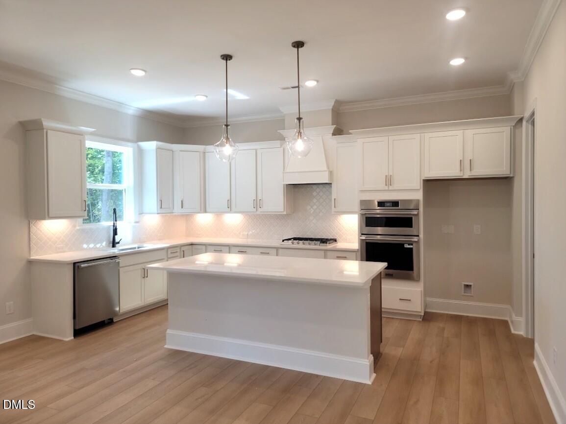 Bright kitchen with white cabinetry, large island, and double ovens in The Crawford D floor plan by Davidson Homes, Wake Forest, NC