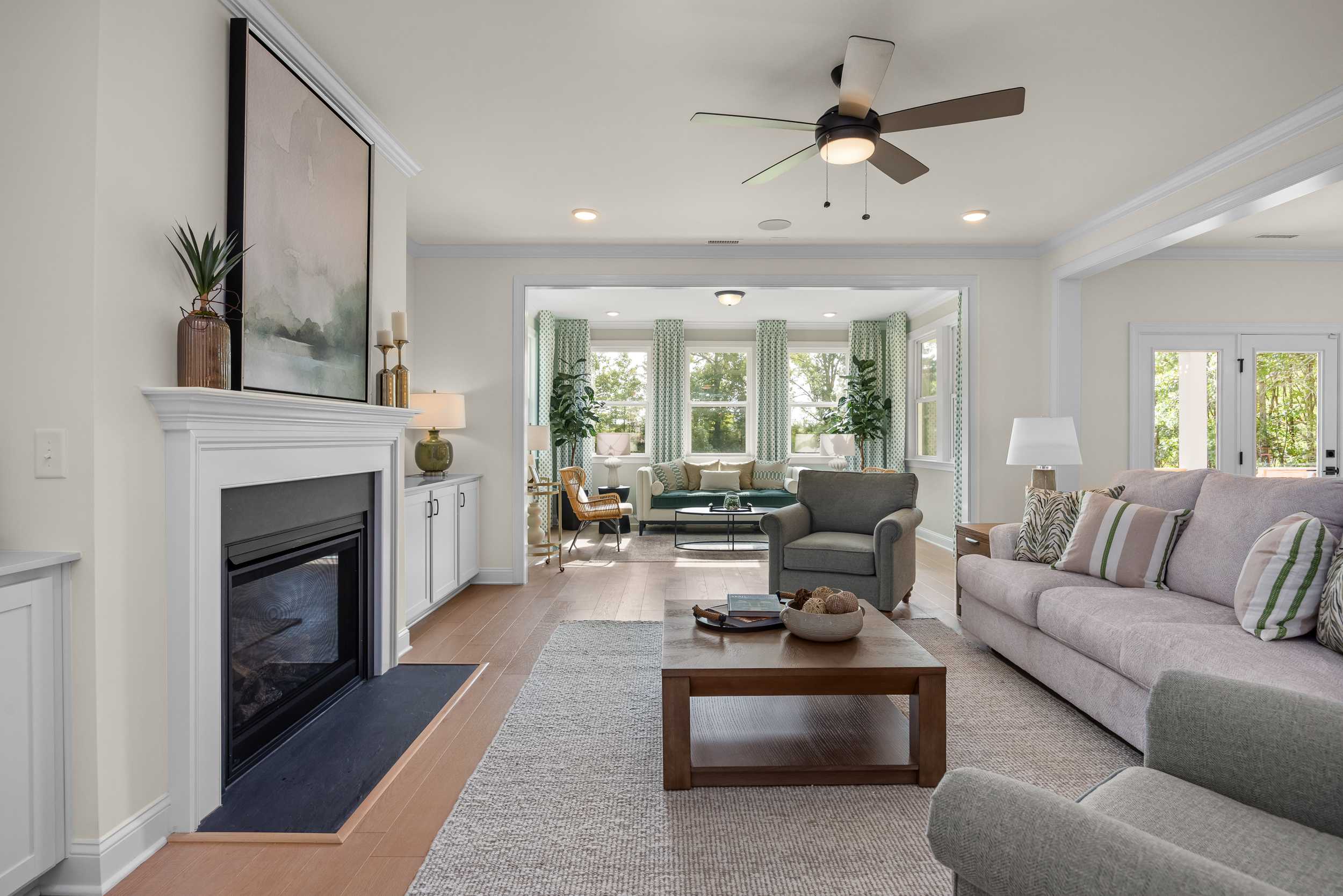 Cozy open-concept living room with gas fireplace, ceiling fan, and large windows at Laneridge Estates in Raleigh, North Carolina