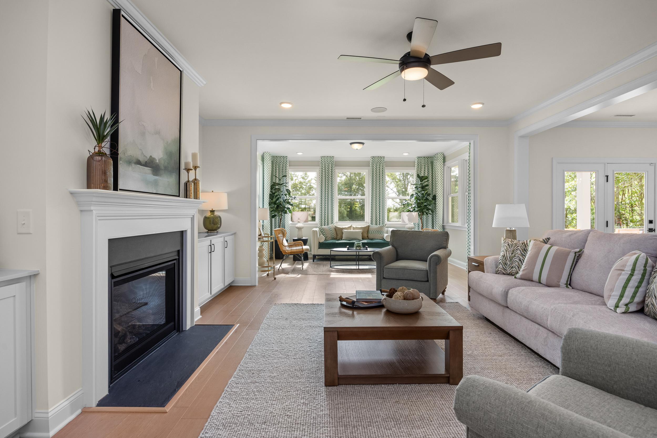 Cozy open-concept living room with gas fireplace, ceiling fan, and large windows at Laneridge Estates in Raleigh, North Carolina
