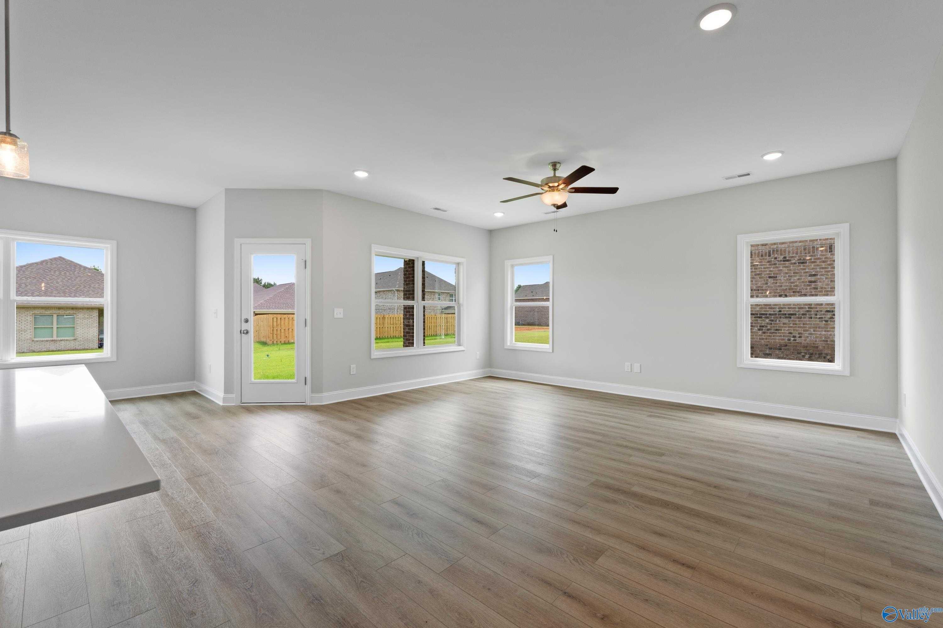 Bright open living room with hardwood floors, large windows to backyard, ceiling fan in Davidson Homes The Franklin C, Harvest, Alabama