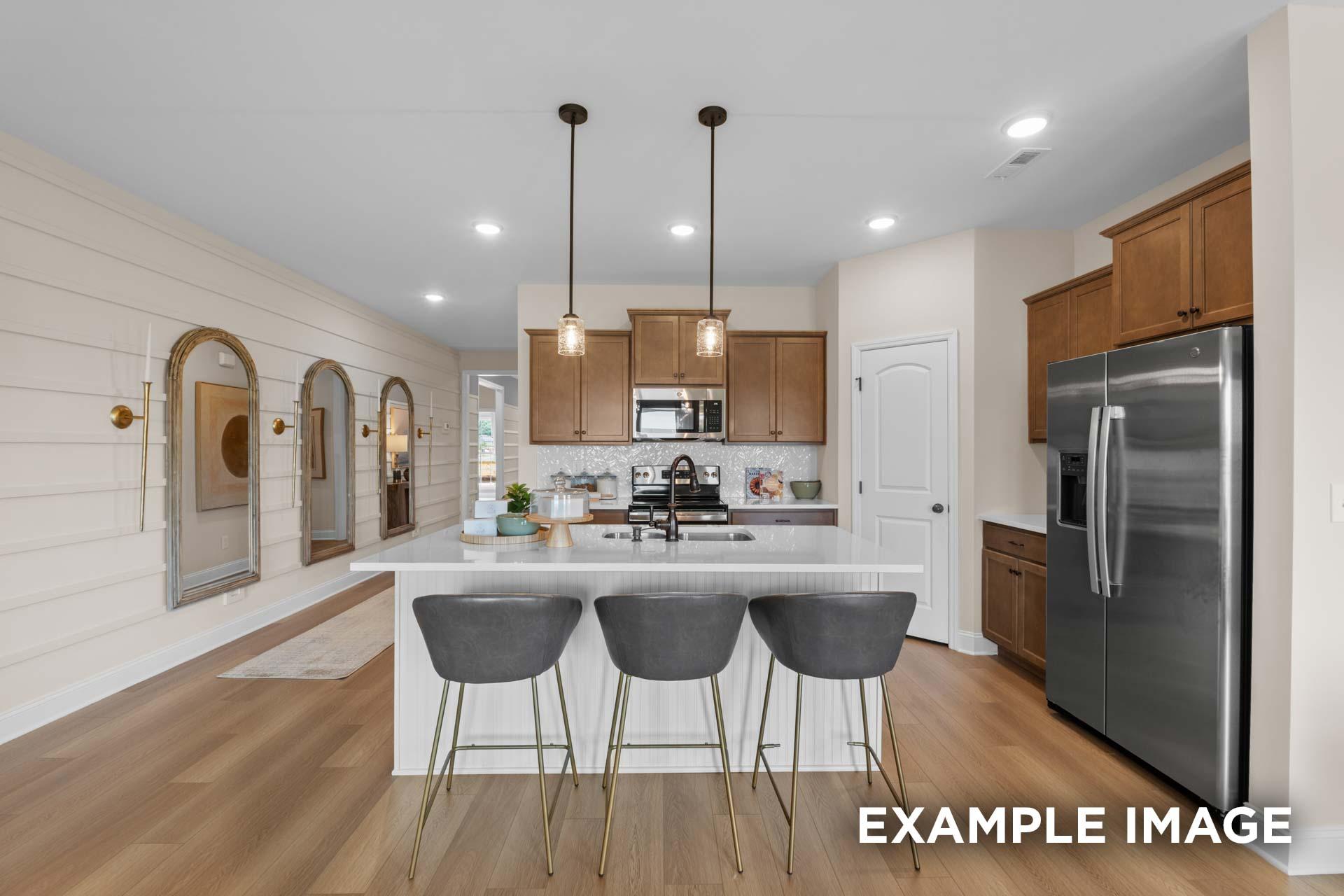 Spacious kitchen in The Laurel M home with white island, bar stools, stainless steel appliances, and open layout
