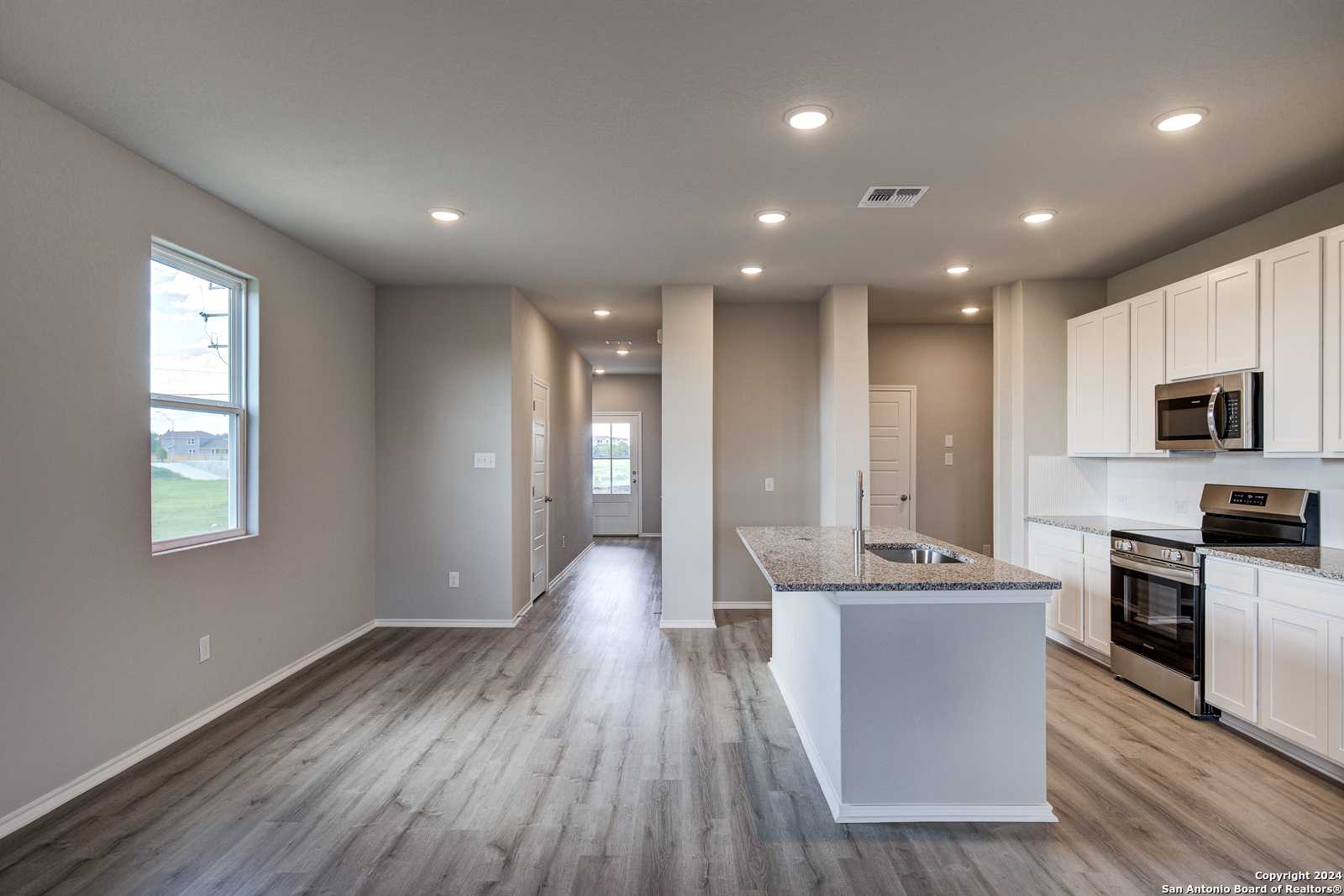 Modern open kitchen with white cabinets, granite island, stainless appliances in The Blanco C, Davidson Homes, San Antonio