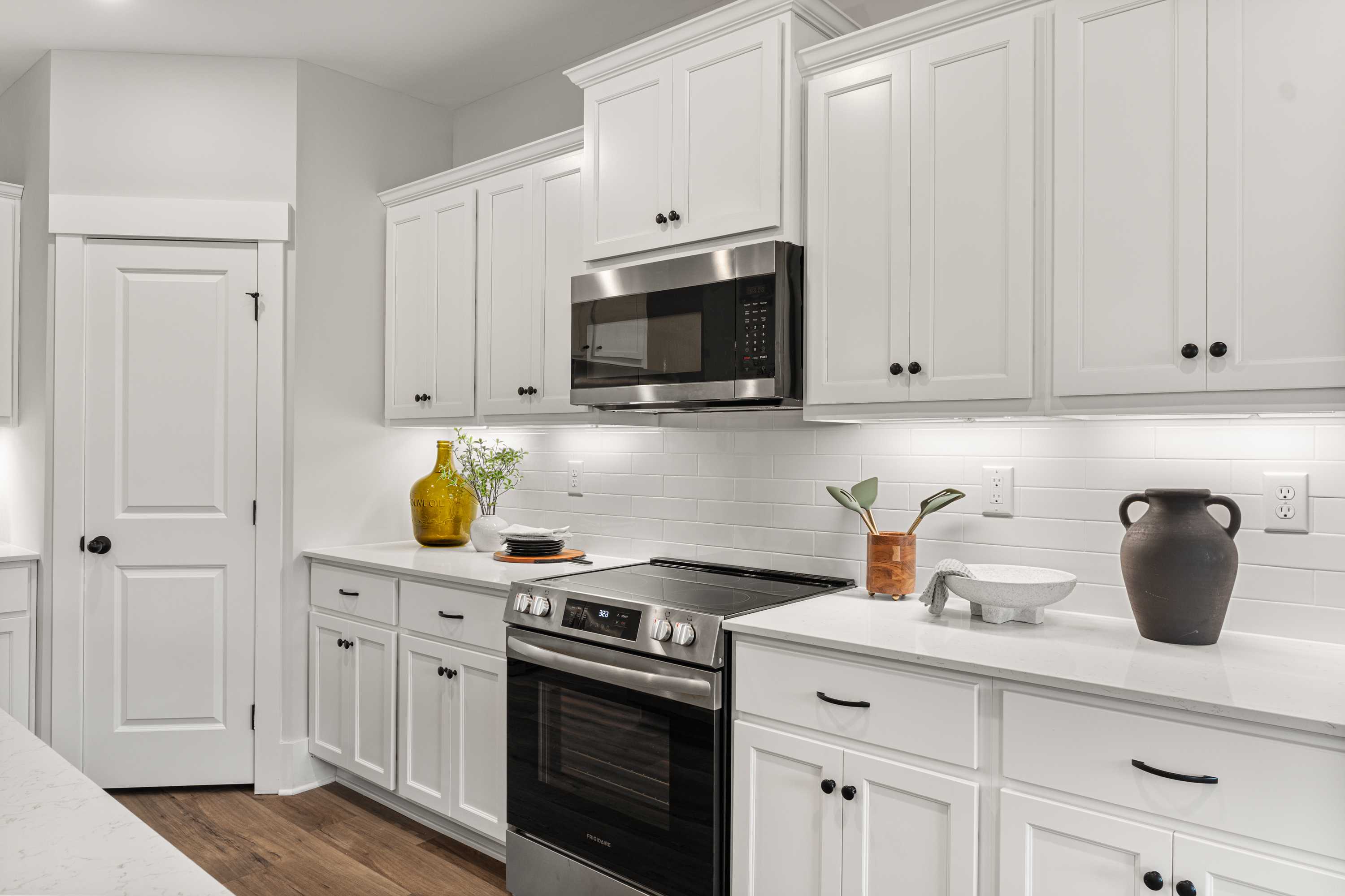 Modern kitchen at River Road Estates in Decatur Alabama with white shaker cabinets, stainless steel appliances, quartz counters, subway tile backsplash