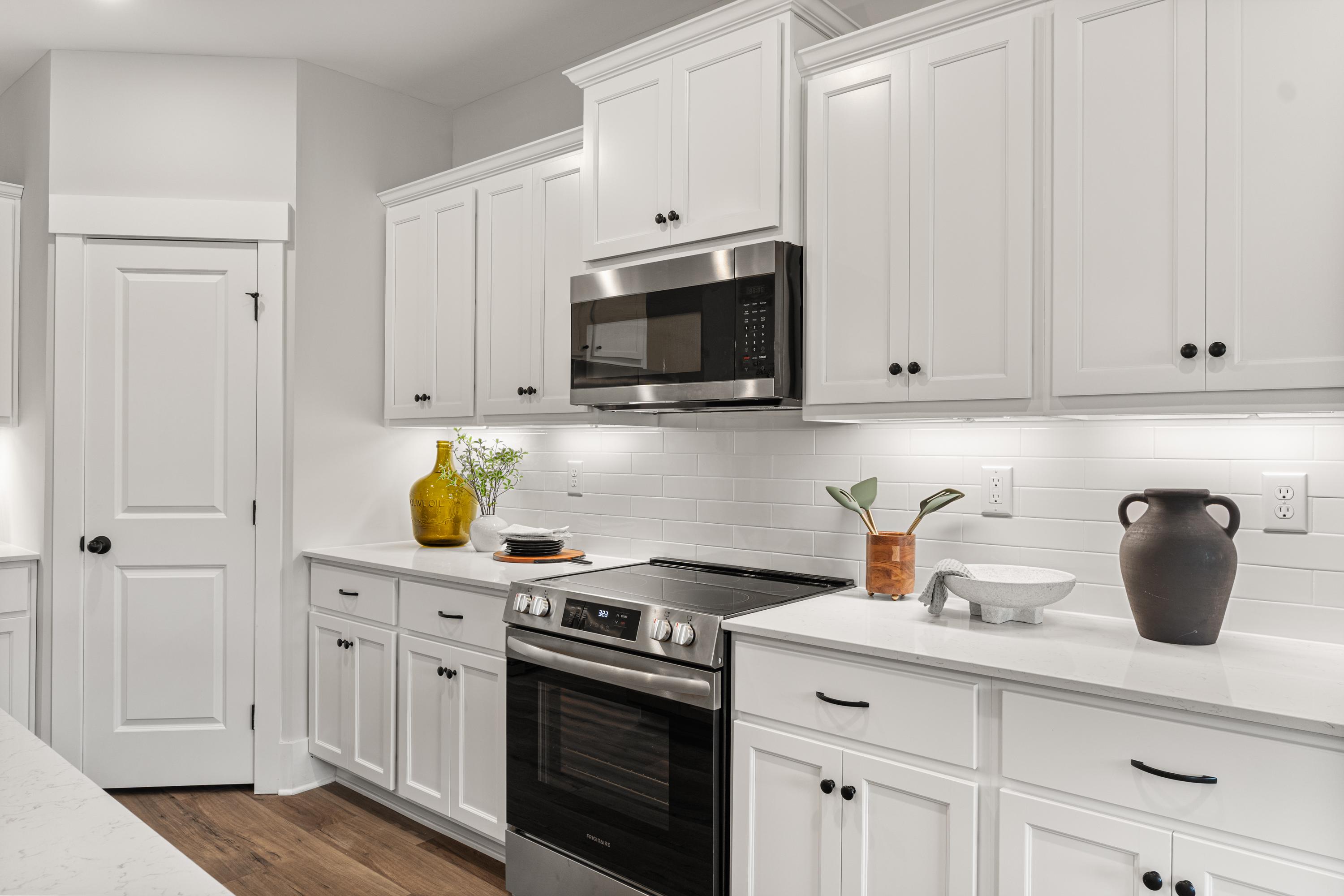 Modern kitchen at River Road Estates in Decatur Alabama with white shaker cabinets, stainless steel appliances, quartz counters, subway tile backsplash