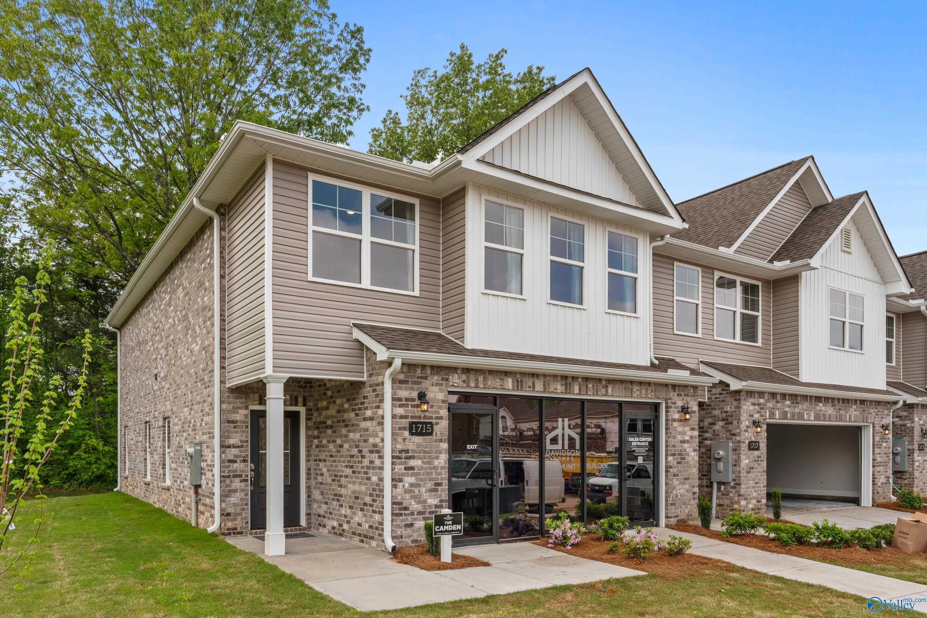 Modern two-story townhome with beige brick facade, two-car garage, and columned porch in Pavilion, Huntsville, Alabama - The Camden by Davidson Homes